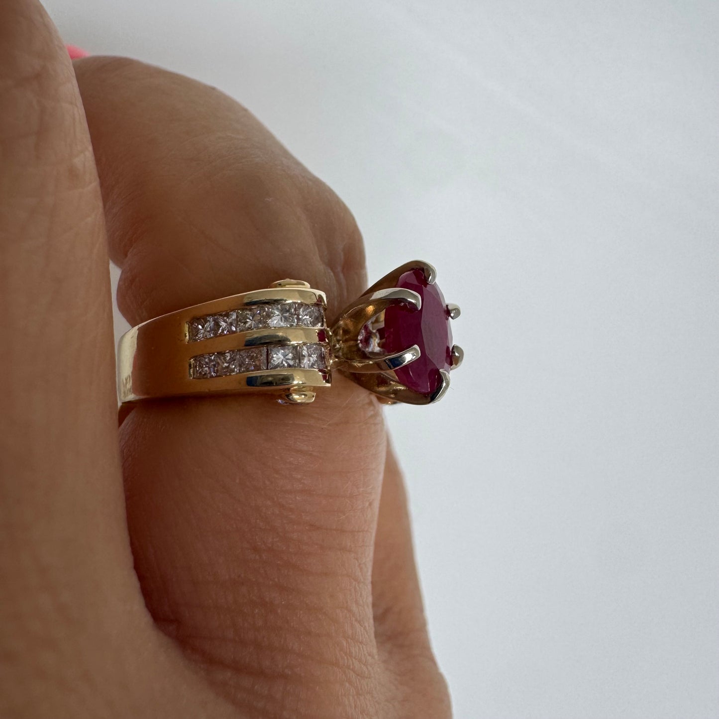 14K gold ring set with a vivid natural Ruby at the center and accented by rows of Diamonds on both sides.