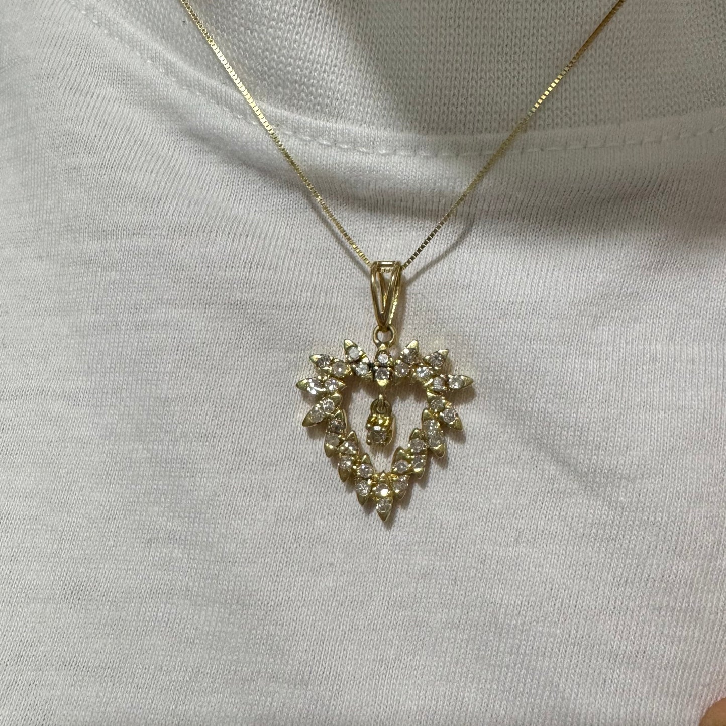 תליון זהב צהוב 14 קראט בצורת לב, משובץ יהלומים בסידור עדין היוצר מראה עשיר ומלא ברק.