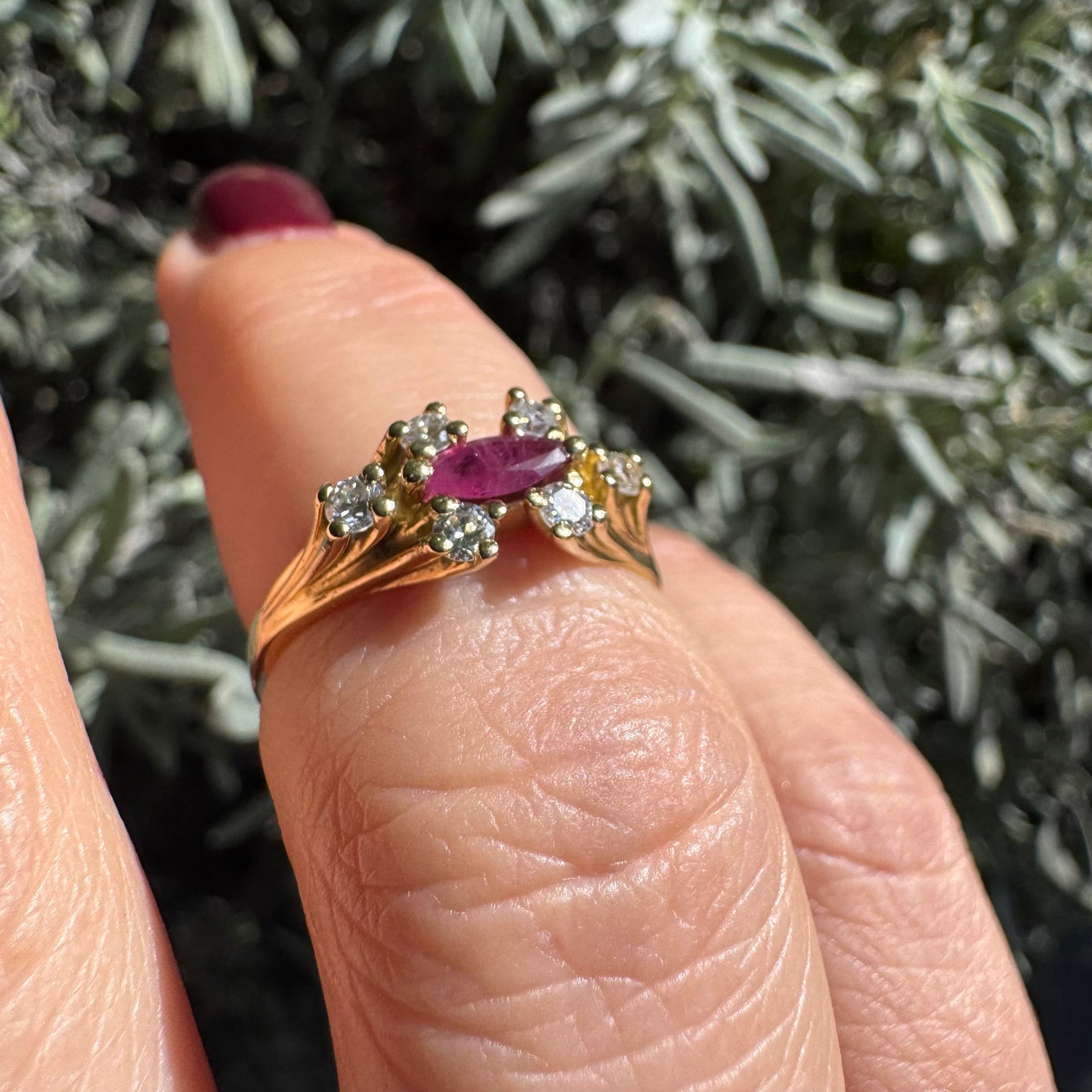 18K gold ring set with a marquise-cut Ruby accented by round Diamonds on each side.