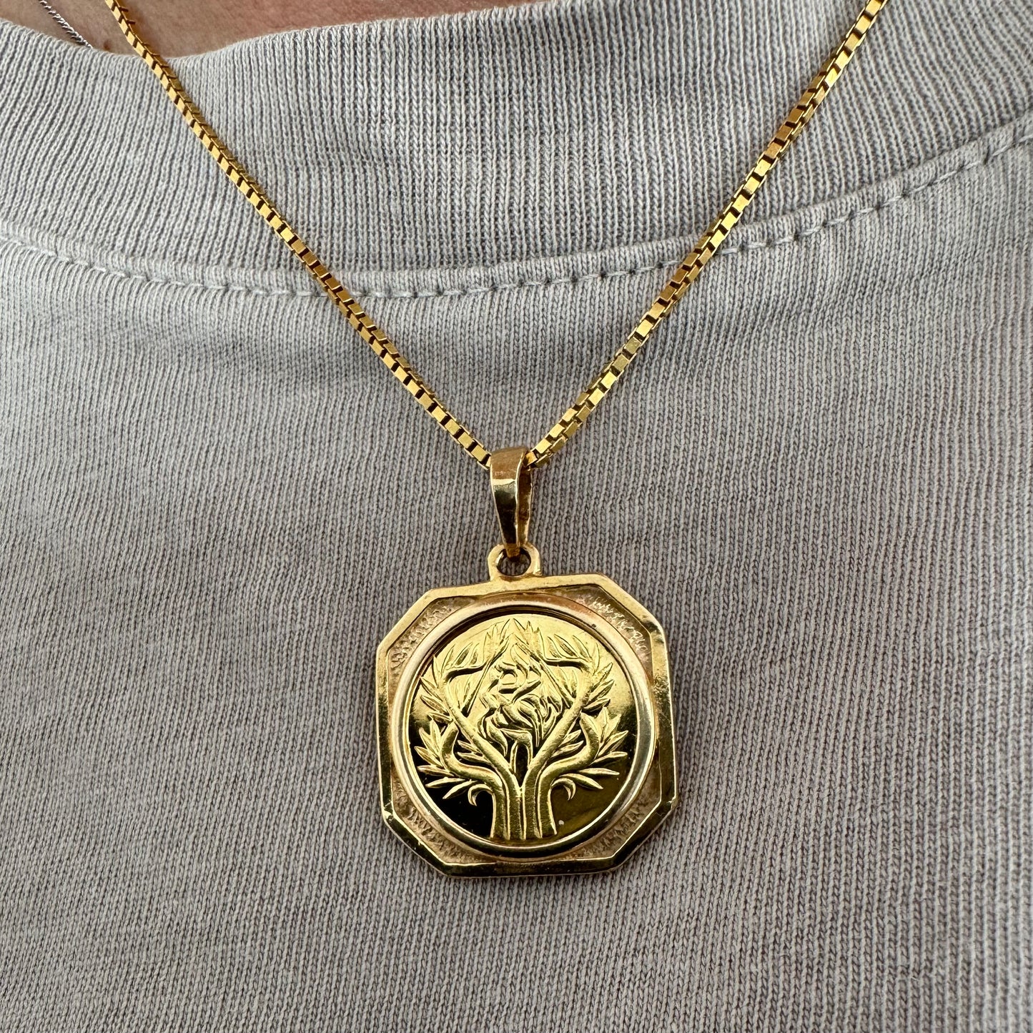 תליון זהב צהוב 14 קראט בעיצוב קלאסי עם נוכחות סמלית חזקה. במרכז התליון חריטה עדינה של עץ חיים, סמל לצמיחה, חיבור ושפע וכיתוב ״שמע ישראל״ ובצד השני אותיות ה-א״ב.