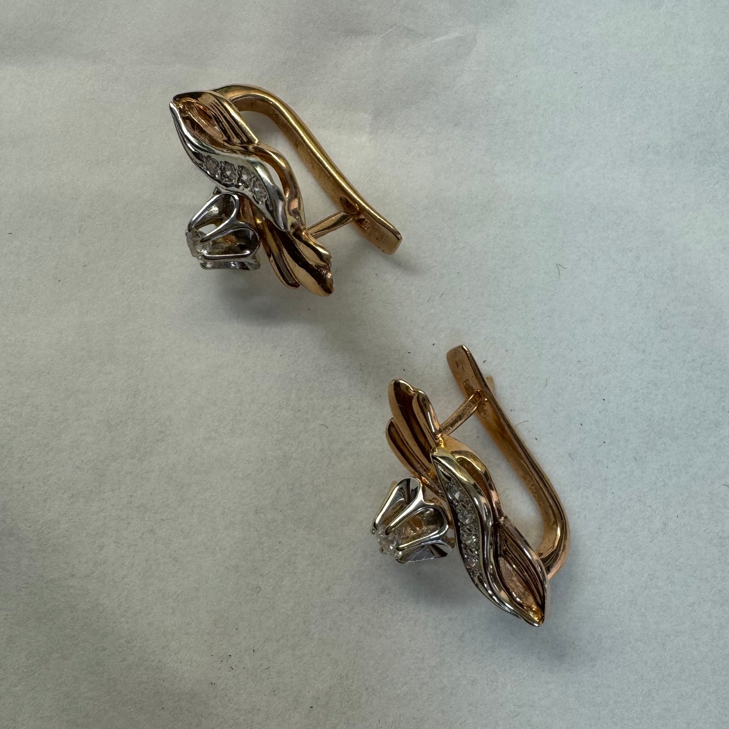 עגילי זהב 14 קראט בעיצוב מתעגל ואלגנטי המשובצים יהלומים נוצצים .