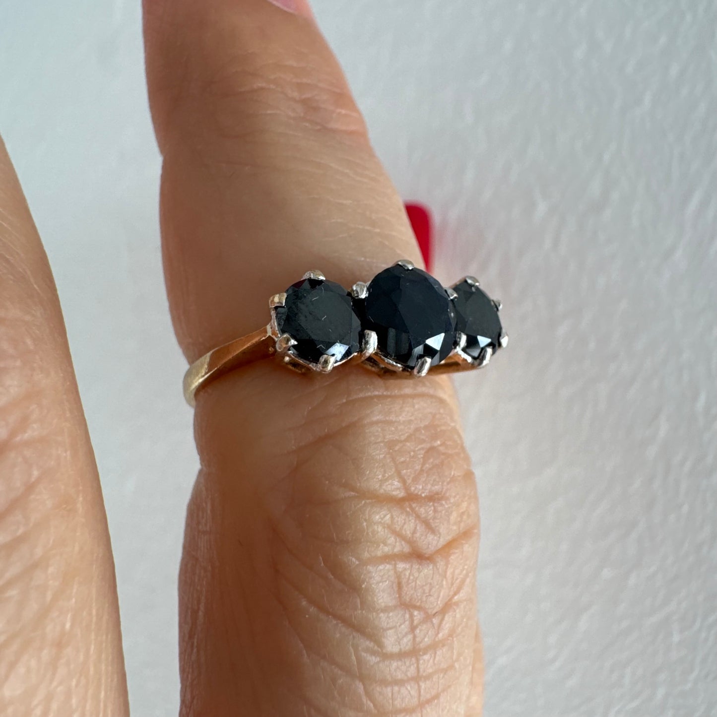 טבעת זהב 10 קראט משובצת שלוש אבני ספיר בצבע כחול כהה בחיתוך עגול, בעיצוב קלאסי עם נוכחות עמוקה ואלגנטית.