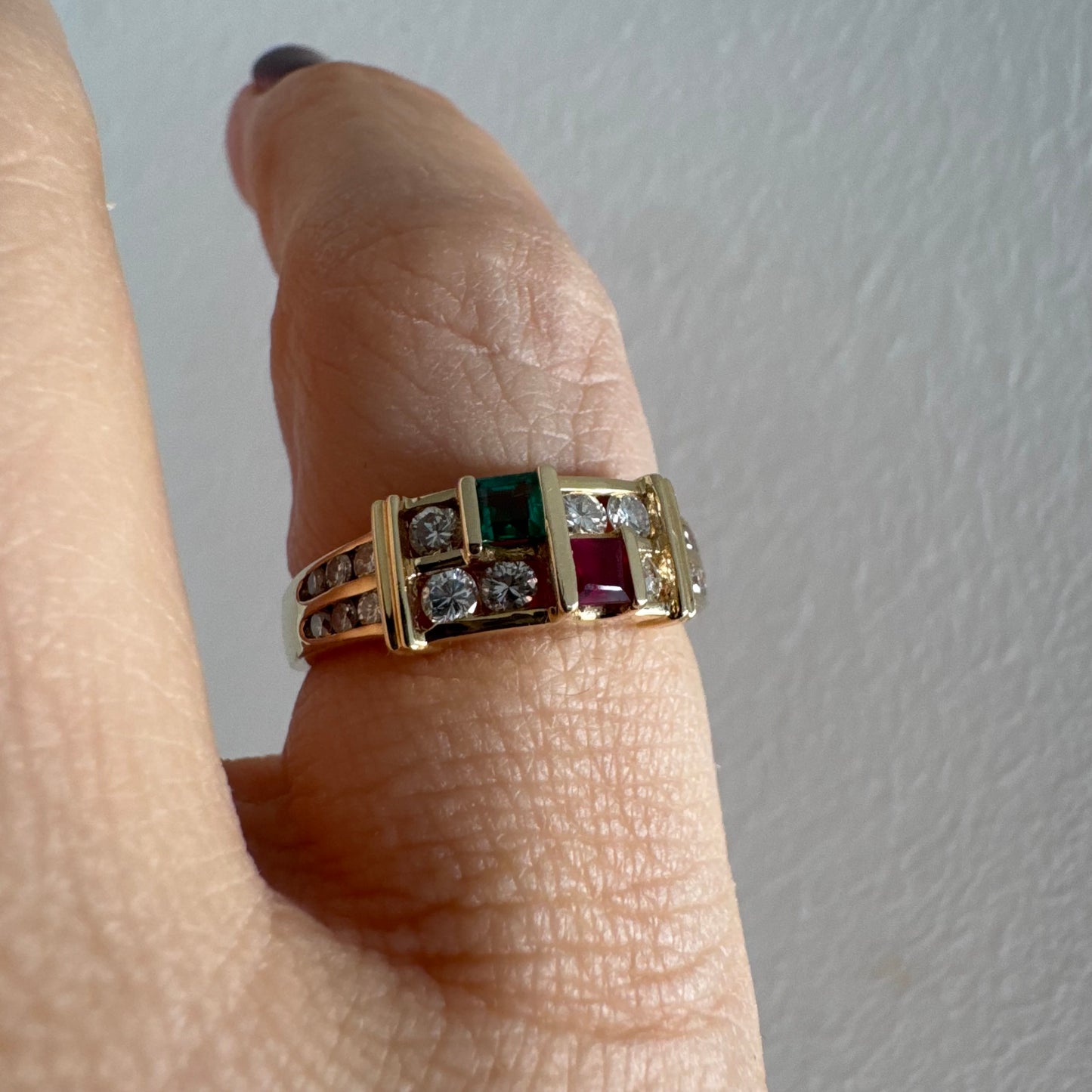 טבעת זהב צהוב 18 קראט בעיצוב גאומטרי מדורג, משובצת יהלומים עגולים לצד אבני אמרלד ורובי בחיתוך מלבני.