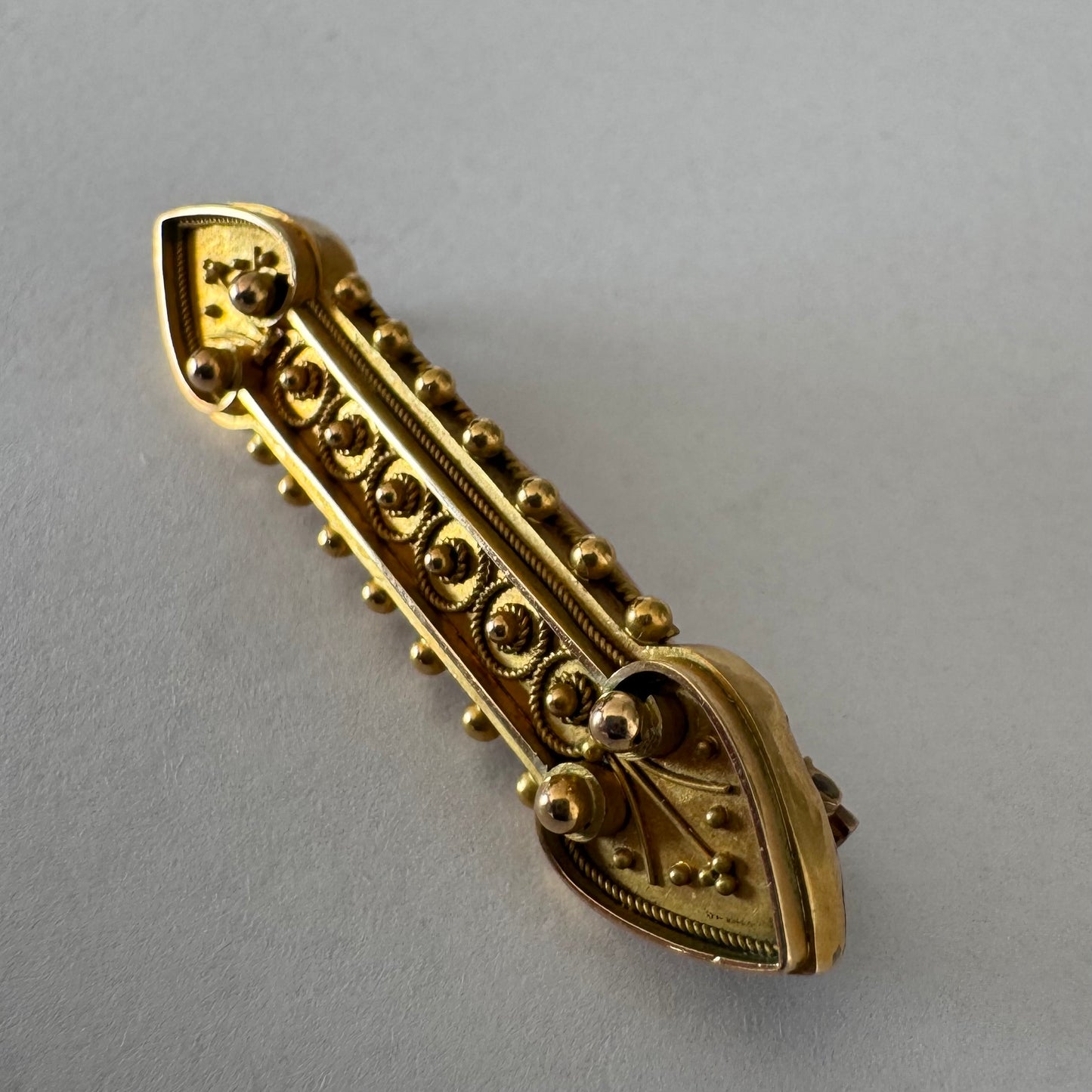 14K gold brooch featuring an ornate geometric design with intricate gold detailing & symmetrical decorative motifs.