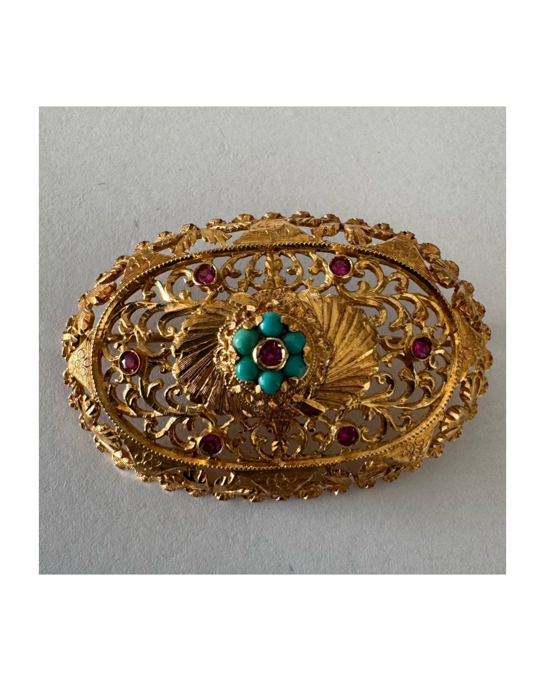 18K gold filigree brooch featuring intricate openwork detailing, accented with Ruby & Turquoise arranged in a floral centerpiece