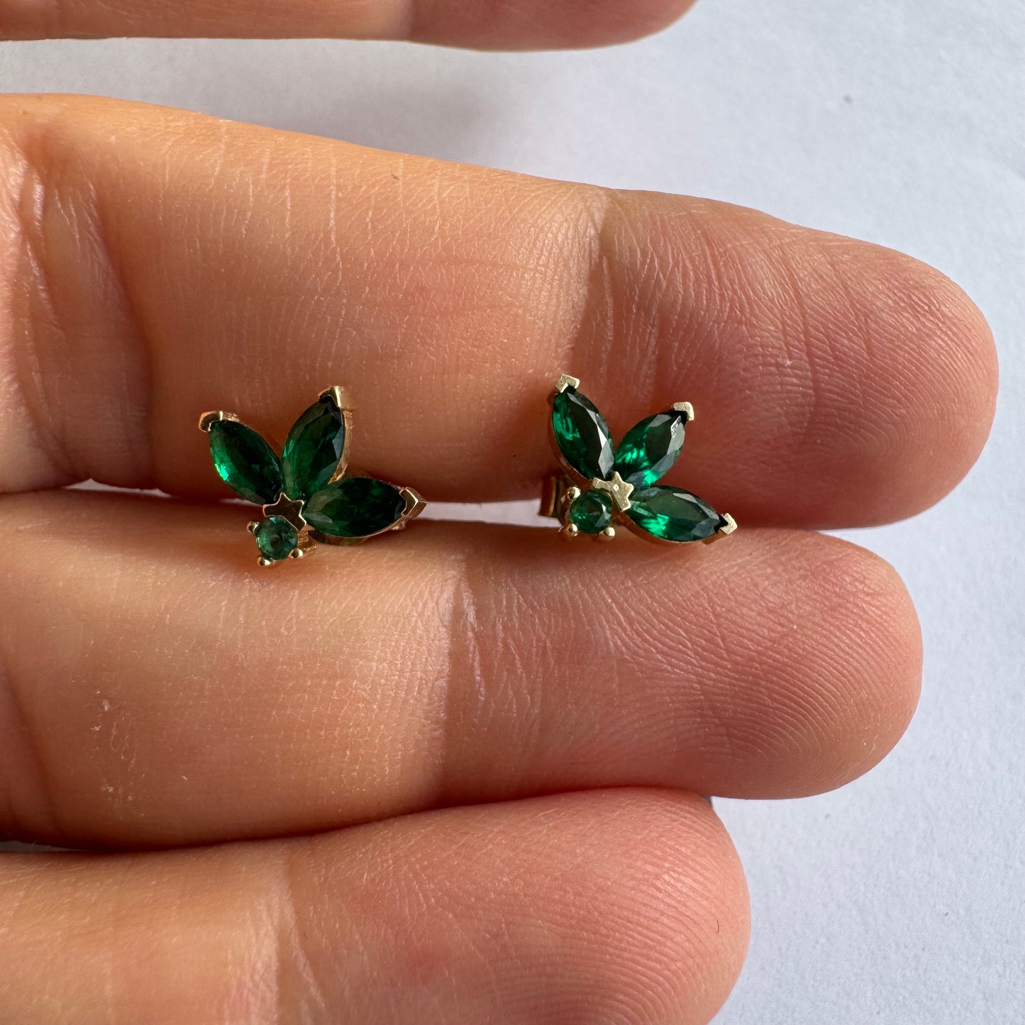 עגילים צמודיפ לאוזן מזהב 14 קראט, בעיצוב פרח עדין משובצים אבני אמרלד בחיתוך מרקיזה היוצר מראה אלגנטי, נקי ועל-זמני.
