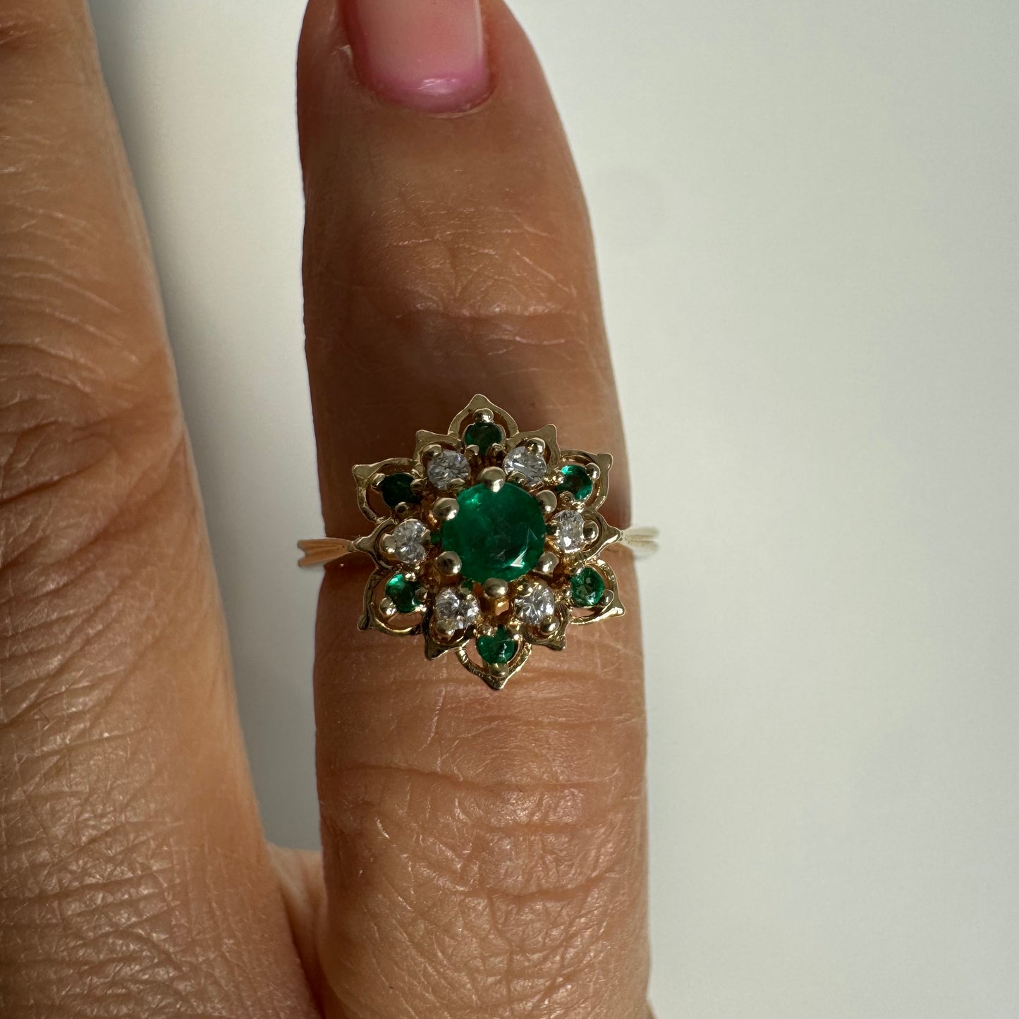 טבעת זהב 14 קראט בעיצוב פרח משובצת אבן אמרלד מרכזית, מוקפת יהלומים ואבני אמרלד נוספות