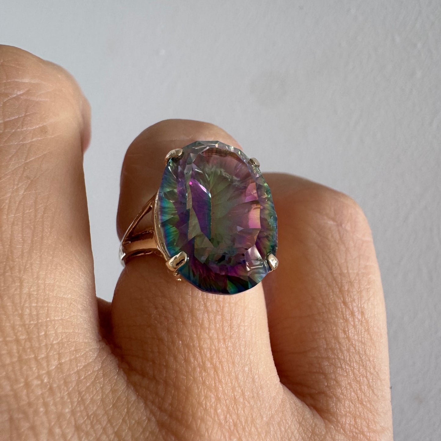 9K gold ring set with a large iridescent stone displaying mesmerizing shades of purple, green, and blue that shift beautifully in the light.