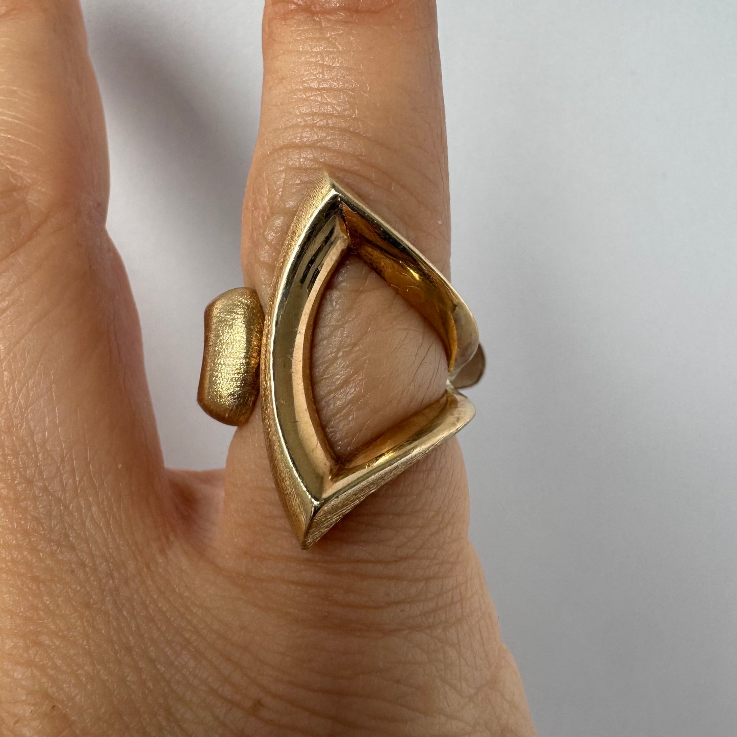 14K gold sculptural ring with a bold, modern design featuring flowing, asymmetrical lines.