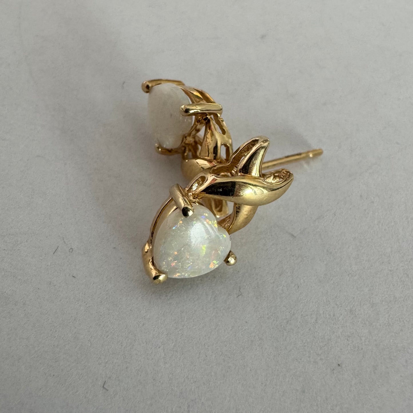 עגילי זהב צהוב 14 קראט משובצים אבני אופל בחיתוך לב, עם משחקי צבע טבעיים בגווני ירוק, ורוד וזהב.