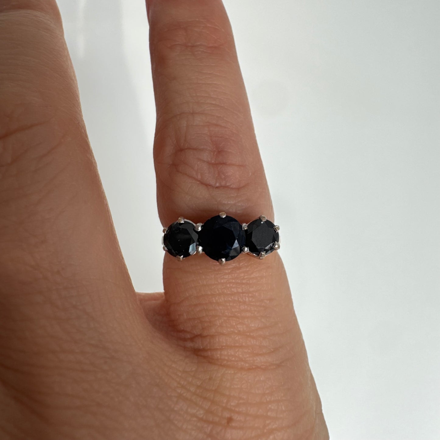 טבעת זהב 10 קראט משובצת שלוש אבני ספיר בצבע כחול כהה בחיתוך עגול, בעיצוב קלאסי עם נוכחות עמוקה ואלגנטית.