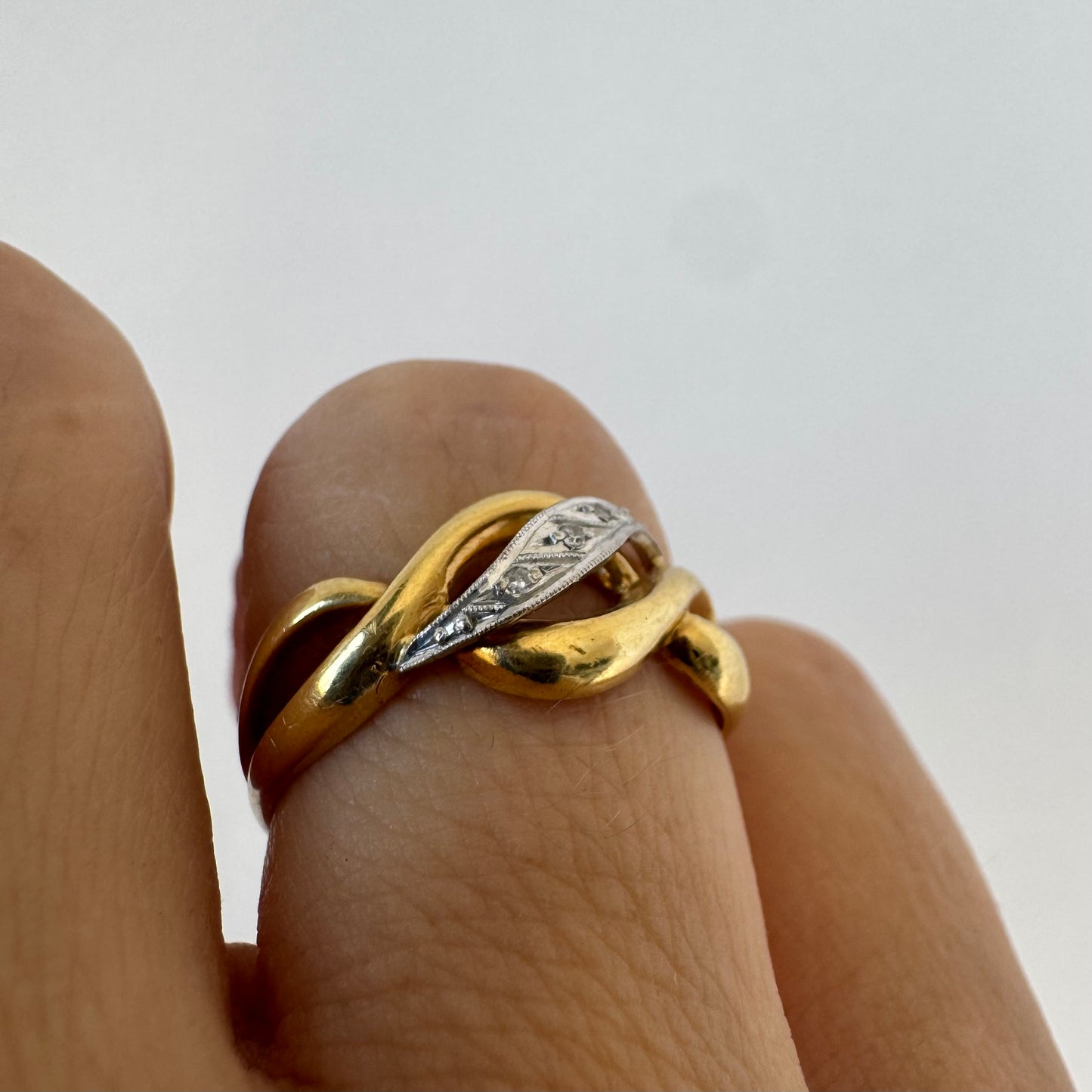 18K gold knot-style ring featuring a white gold center accented with delicate Diamonds.