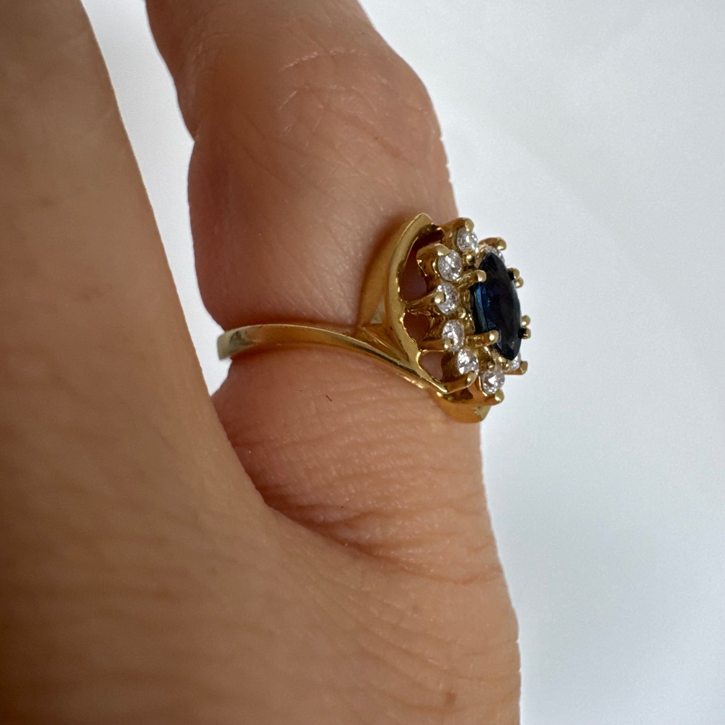 טבעת זהב צהוב 18 קראט משובצת ספיר כחול מרכזי בחיתוך מרקיזה, מוקף הילה של יהלומים המעניקים ניצוץ עדין ומדגישים את צבע האבן העמוק.