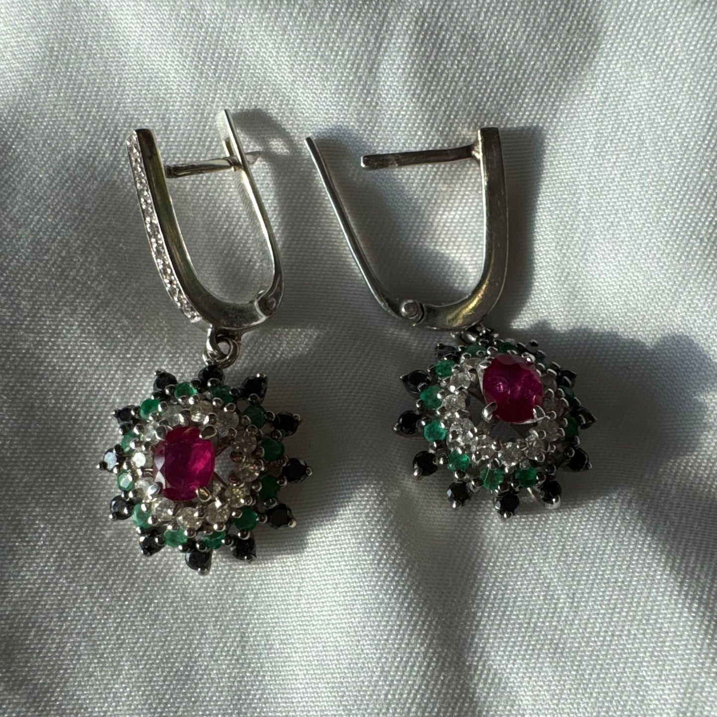 14K white gold drop earrings set with white and black Diamonds, Emeralds and a central Ruby