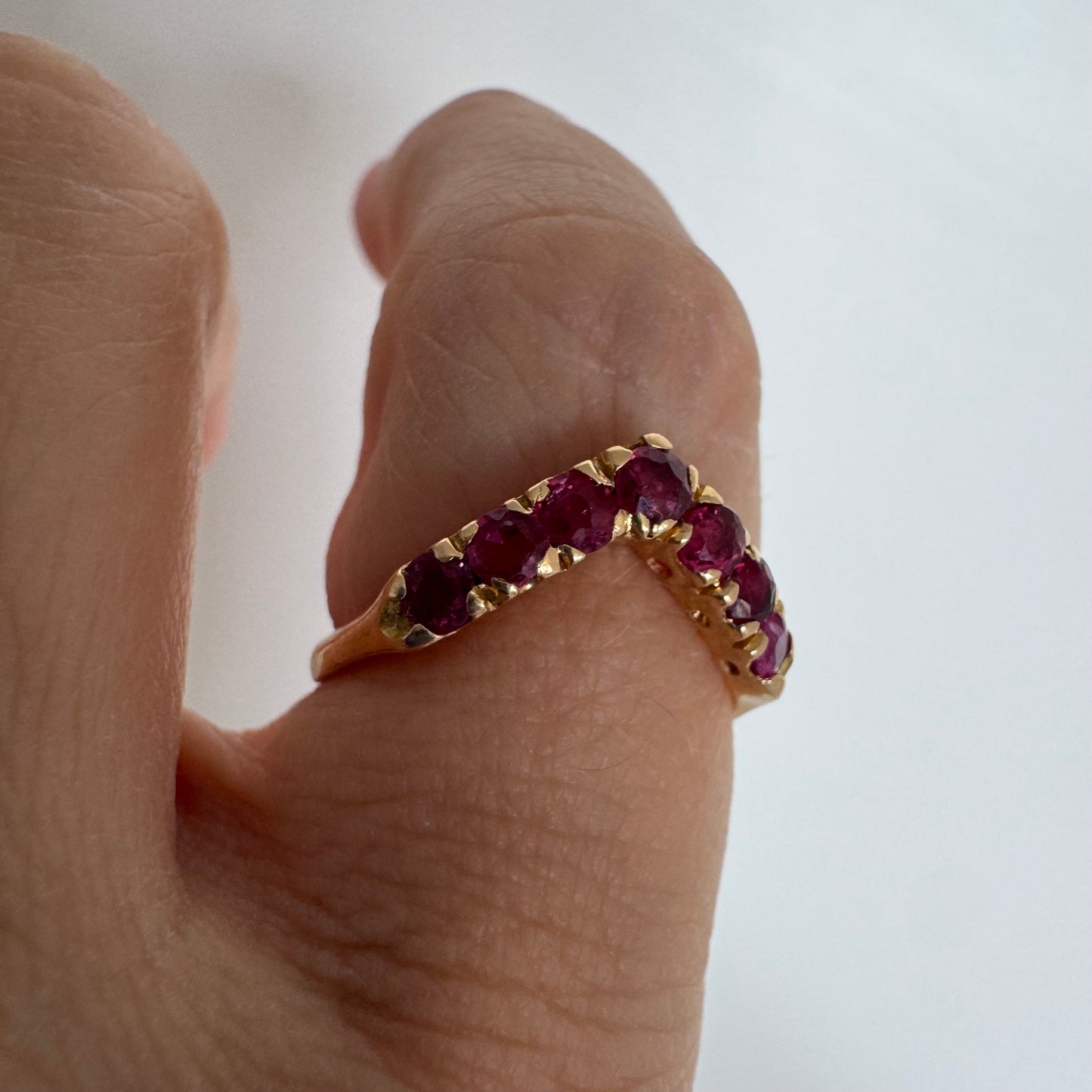 18K gold ring set with vivid red rubies in a distinctive V-shaped design.