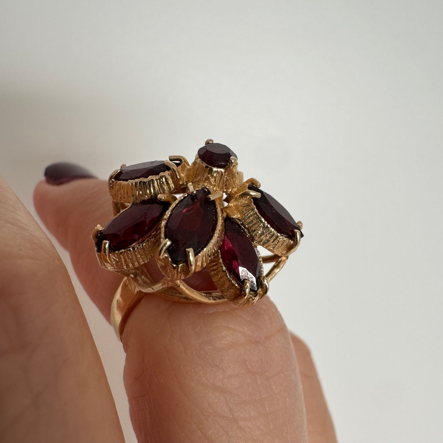 14K gold ring set with marquise-cut Garnets surrounding a round central stone.
