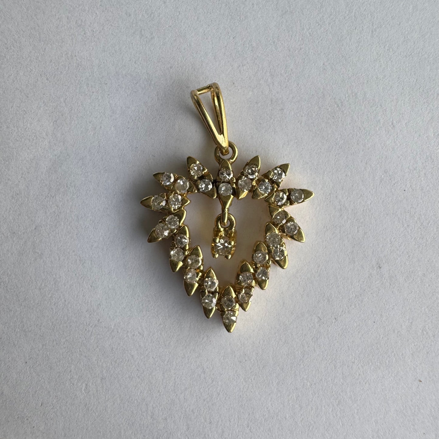 תליון זהב צהוב 14 קראט בצורת לב, משובץ יהלומים בסידור עדין היוצר מראה עשיר ומלא ברק.