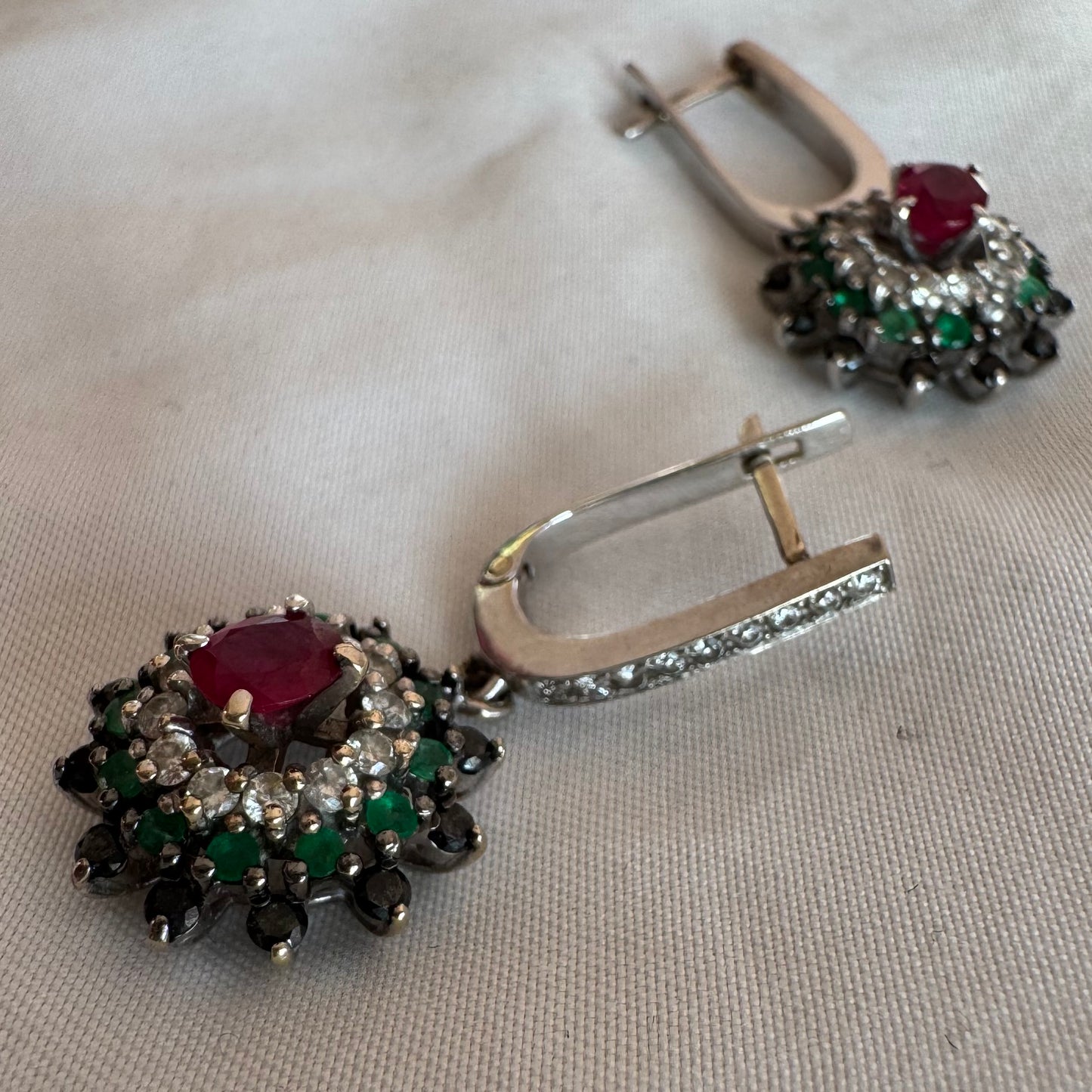 14K white gold drop earrings set with white and black Diamonds, Emeralds and a central Ruby