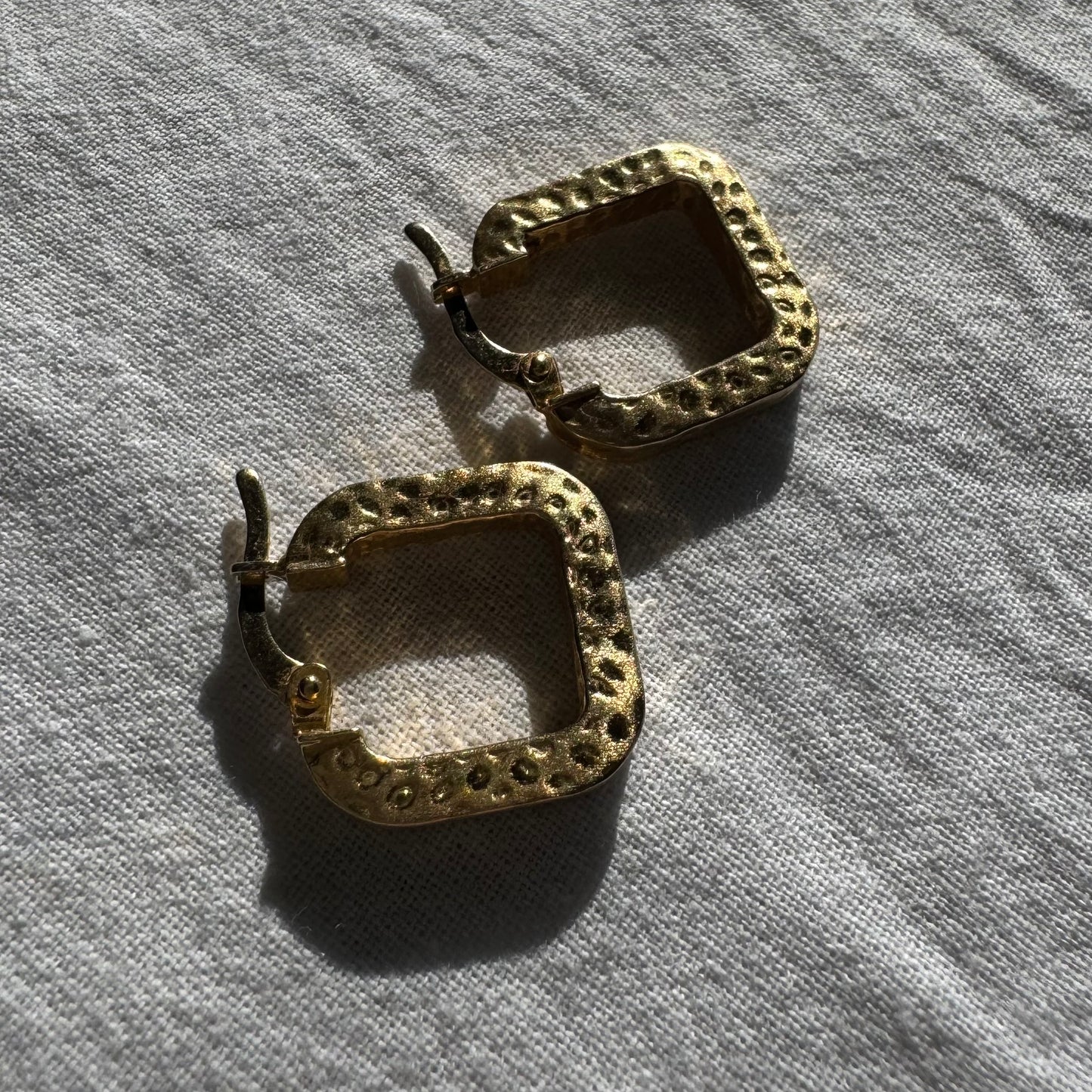 14K gold square hoop earrings with a textured, hammered finish.