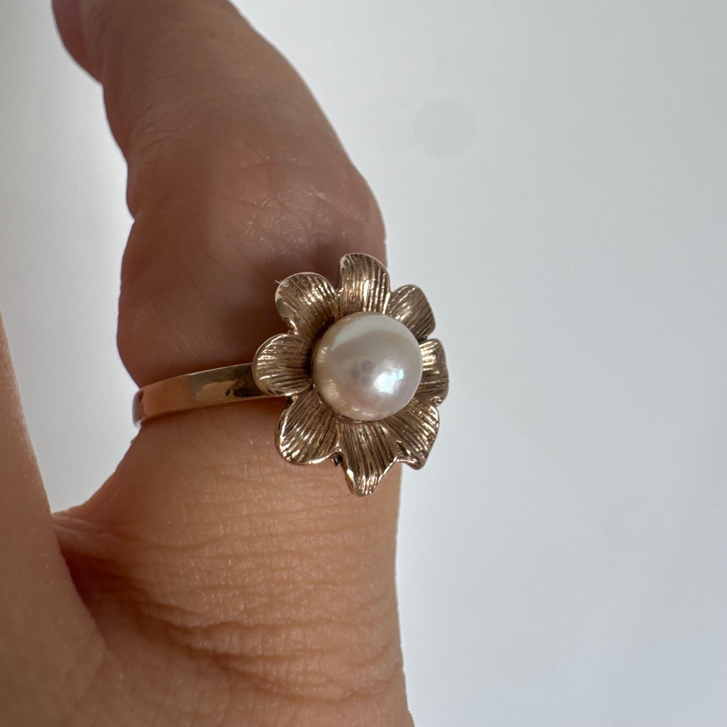9K gold flower ring set with a lustrous Pearl at the center.