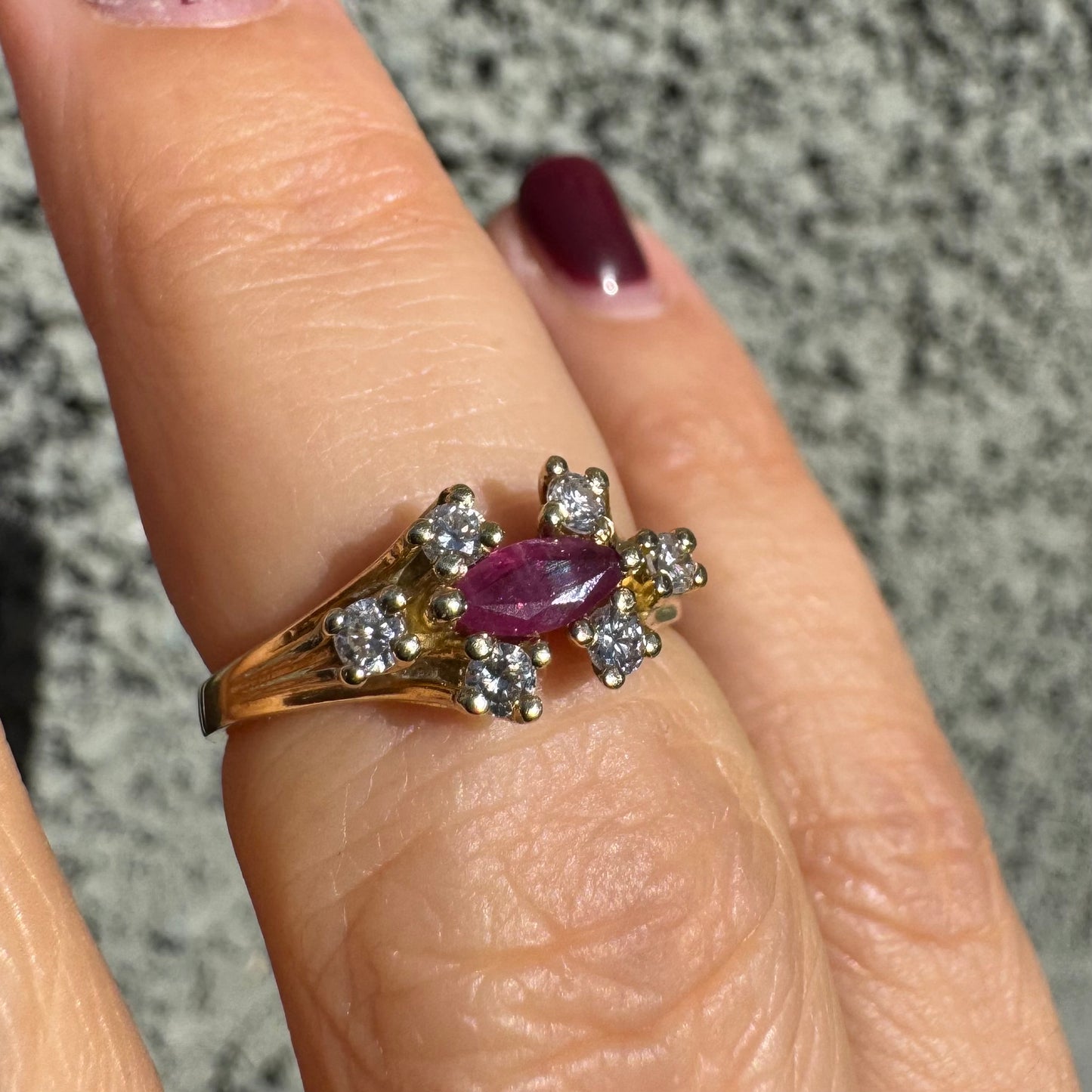 18K gold ring set with a marquise-cut Ruby accented by round Diamonds on each side.