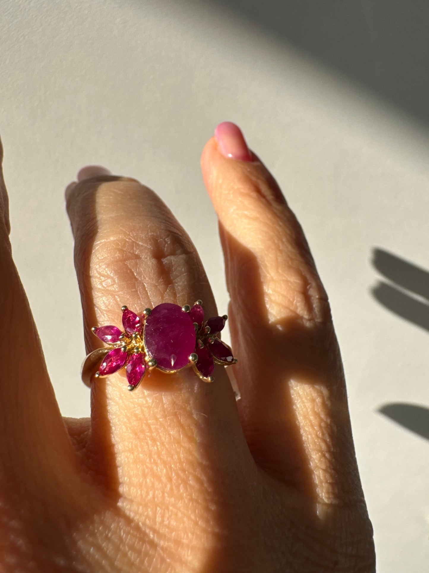 טבעת זהב צהוב 14 קראט משובצת רובי מרכזי גדול ולצידו רובי בחיתוך מרקיזה בעיצוב פרחוני עשיר.