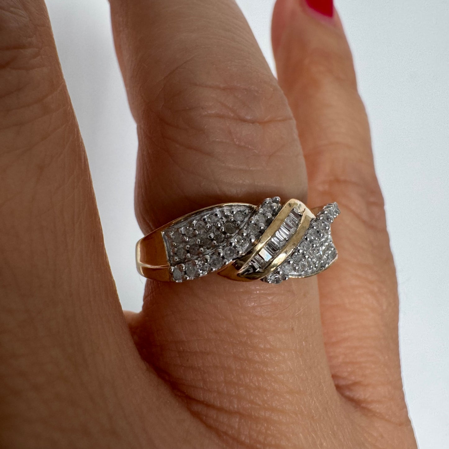 טבעת זהב 10 קראט משובצת יהלומים בחיתוך עגול לצד שורת יהלומי בגט במרכז.