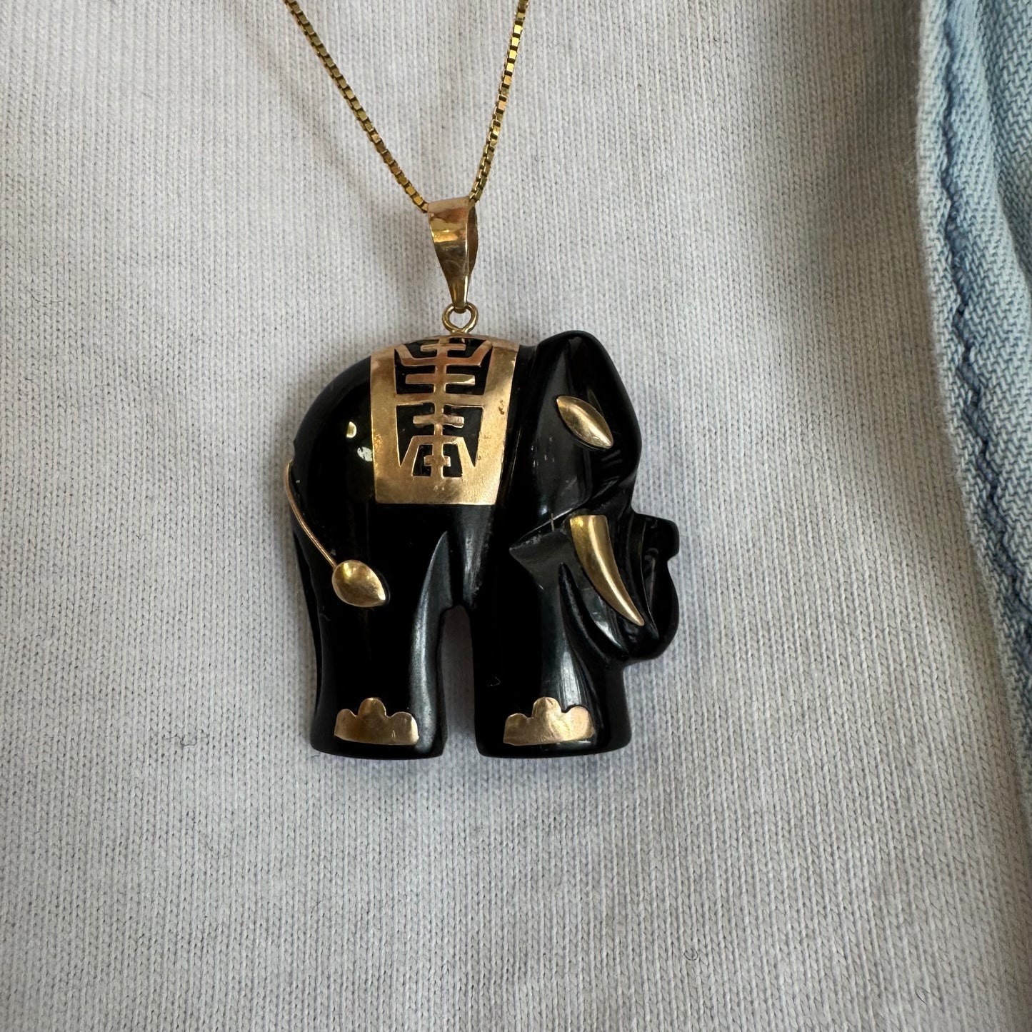 תליון זהב 9 קראט בעיצוב ייחודי ומלא נוכחות של פיל אפריקאי, המשלב גוף שחור מלוטש עם עיטורי זהב עדינים.