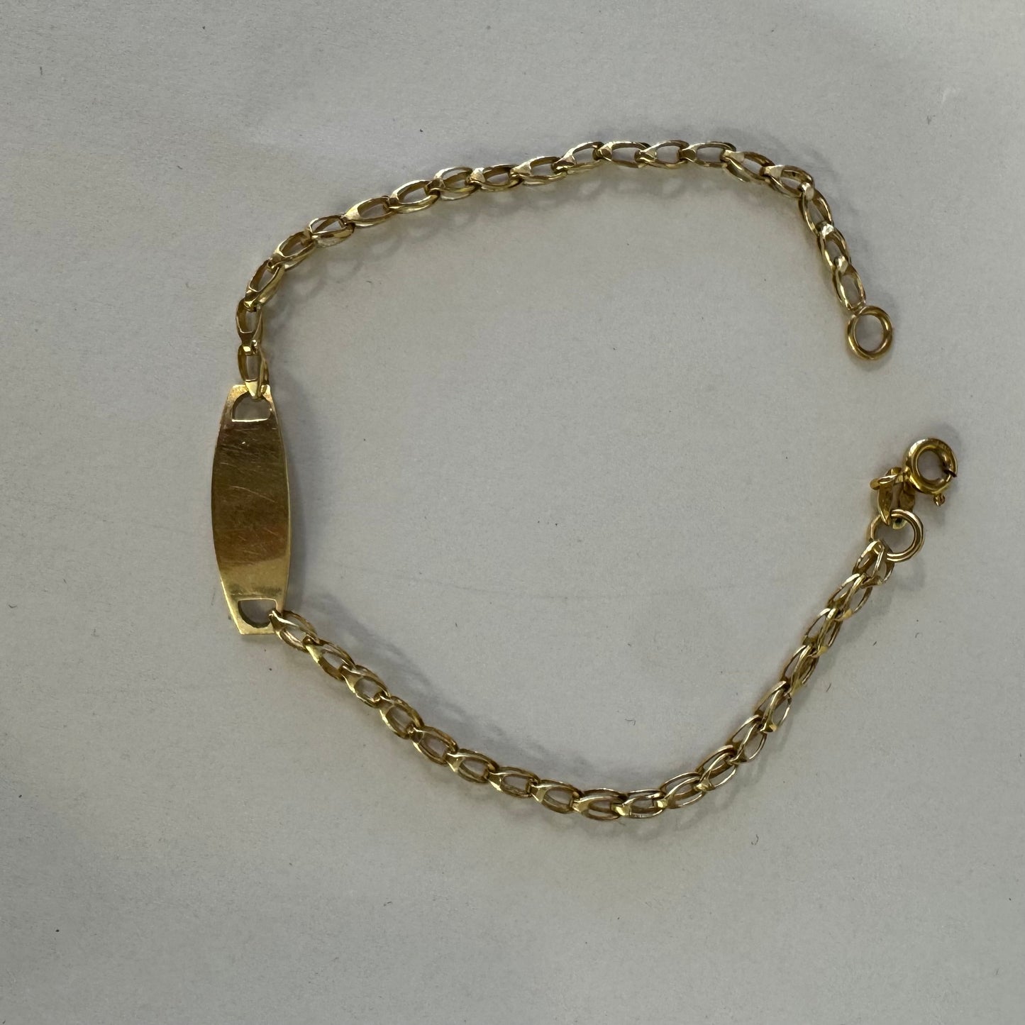 14K gold bracelet featuring a smooth ID plate and a delicate classic chain.
