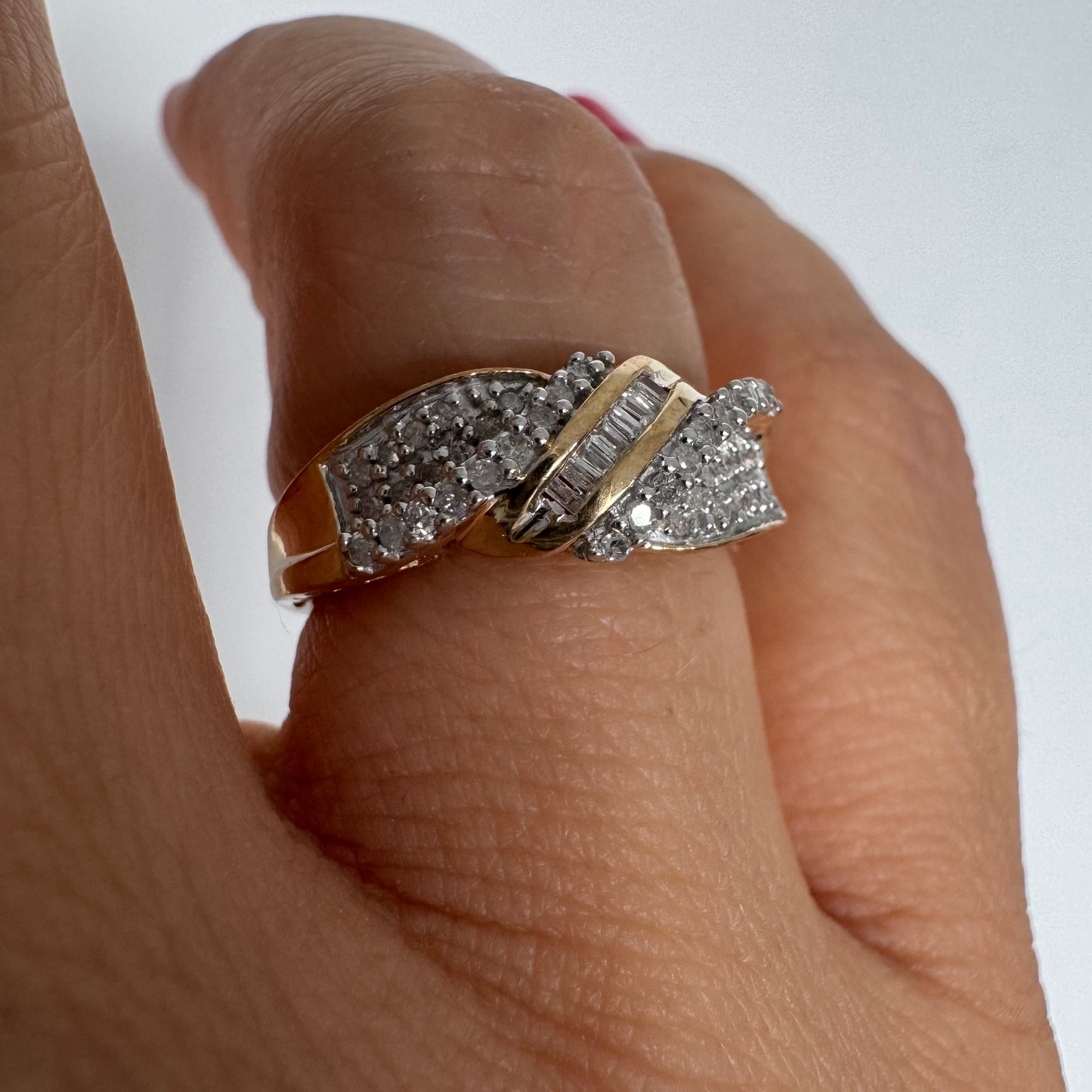 טבעת זהב 10 קראט משובצת יהלומים בחיתוך עגול לצד שורת יהלומי בגט במרכז.