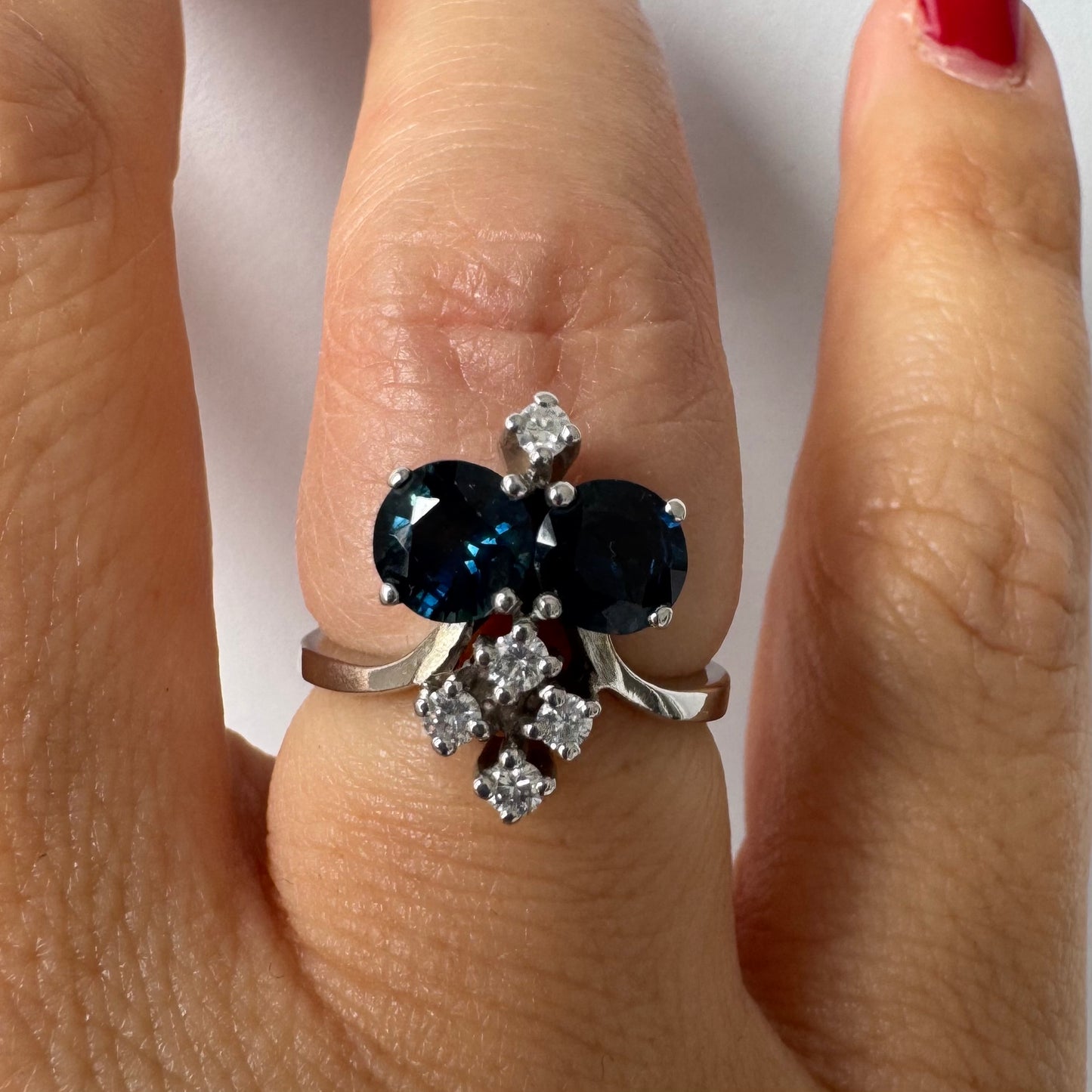 14K gold ring set with two deep blue oval Sapphires accented by clusters of brilliant white Diamonds.