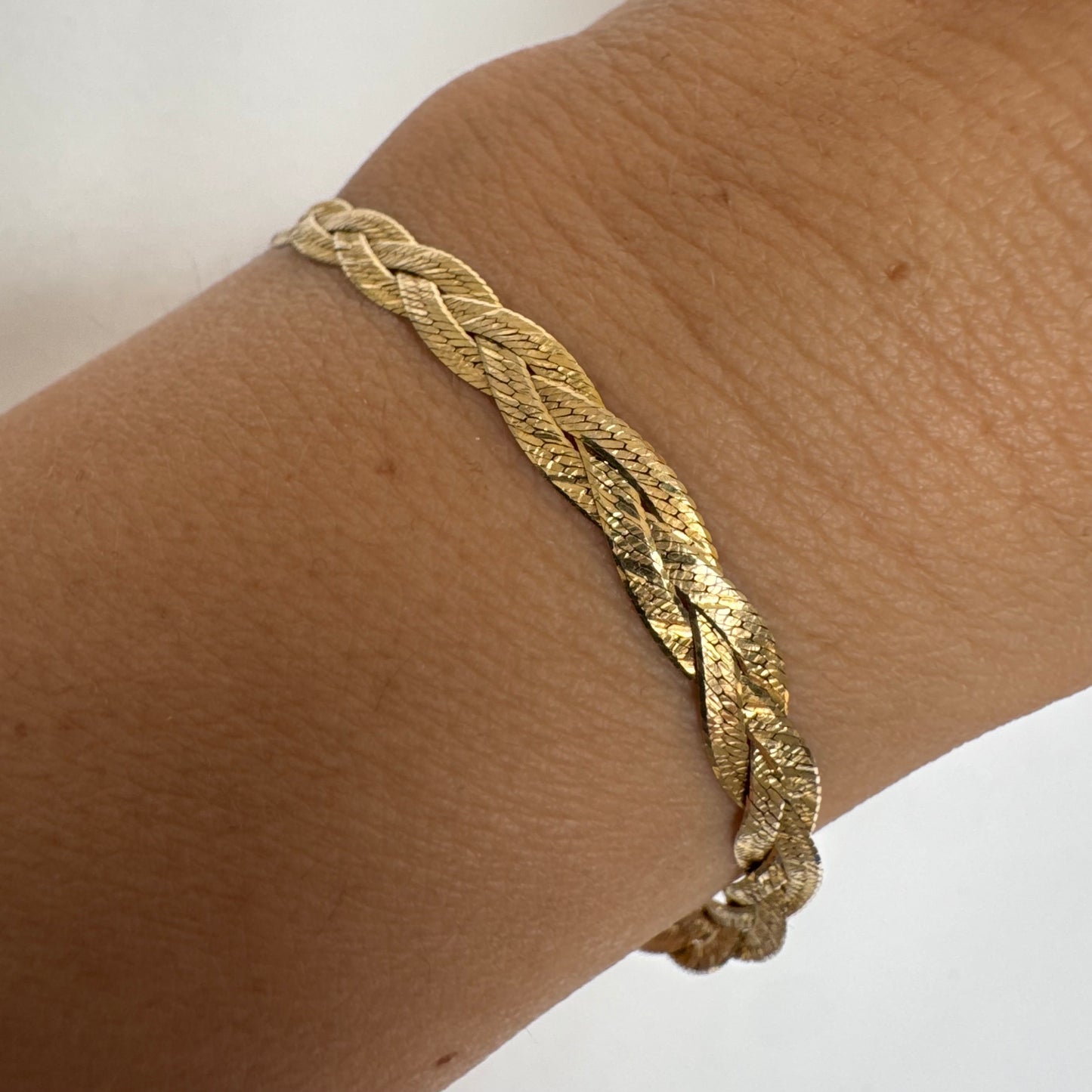 צמיד זהב צהוב 10 קראט בעיצוב קלוע עם טקסטורה עדינה שמחזירה אור וברק רך.