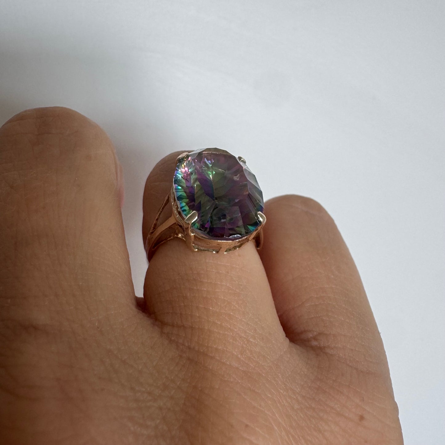 9K gold ring set with a large iridescent stone displaying mesmerizing shades of purple, green, and blue that shift beautifully in the light.