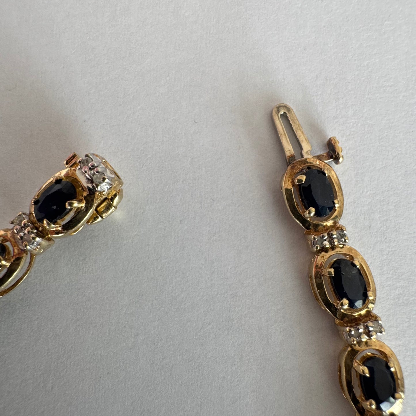 צמיד זהב צהוב 10 קראט בעיצוב קלאסי ועשיר, משובץ אבני ספיר אובליות בגוון כחול עמוק וביניהן שיבוצי יהלומים לבנים עדינים.