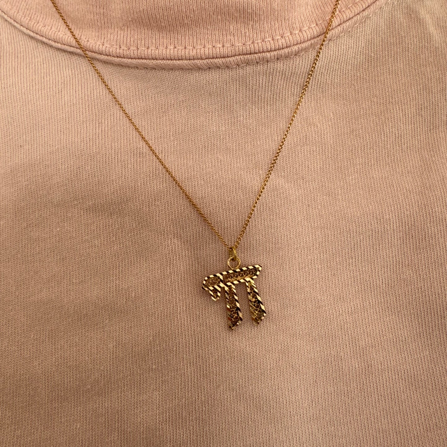 שרשרת זהב אדום 14 קראט עם תליון “חי״, בעיצוב גרפי ובעל נוכחות.