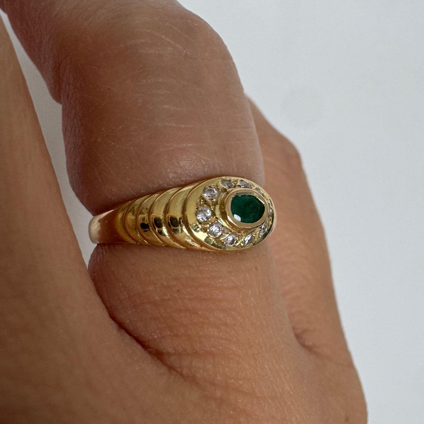 18K gold ring set with an oval Emerald at the center surrounded by Diamonds