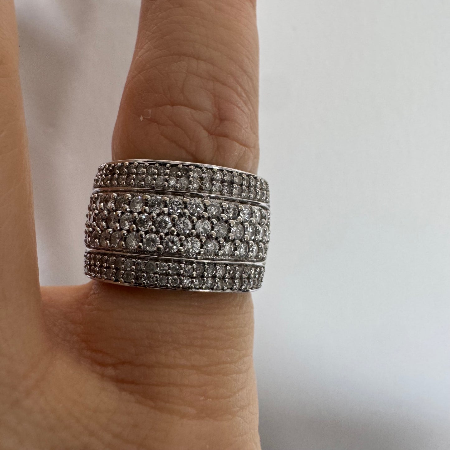 טבעת זהב לבן 18 קראט בעיצוב רחב ומרשים, משובצת יהלומים בשיבוץ פאווה צפוף המעניק ברק עשיר ונוכחות יוקרתית מכל זווית.