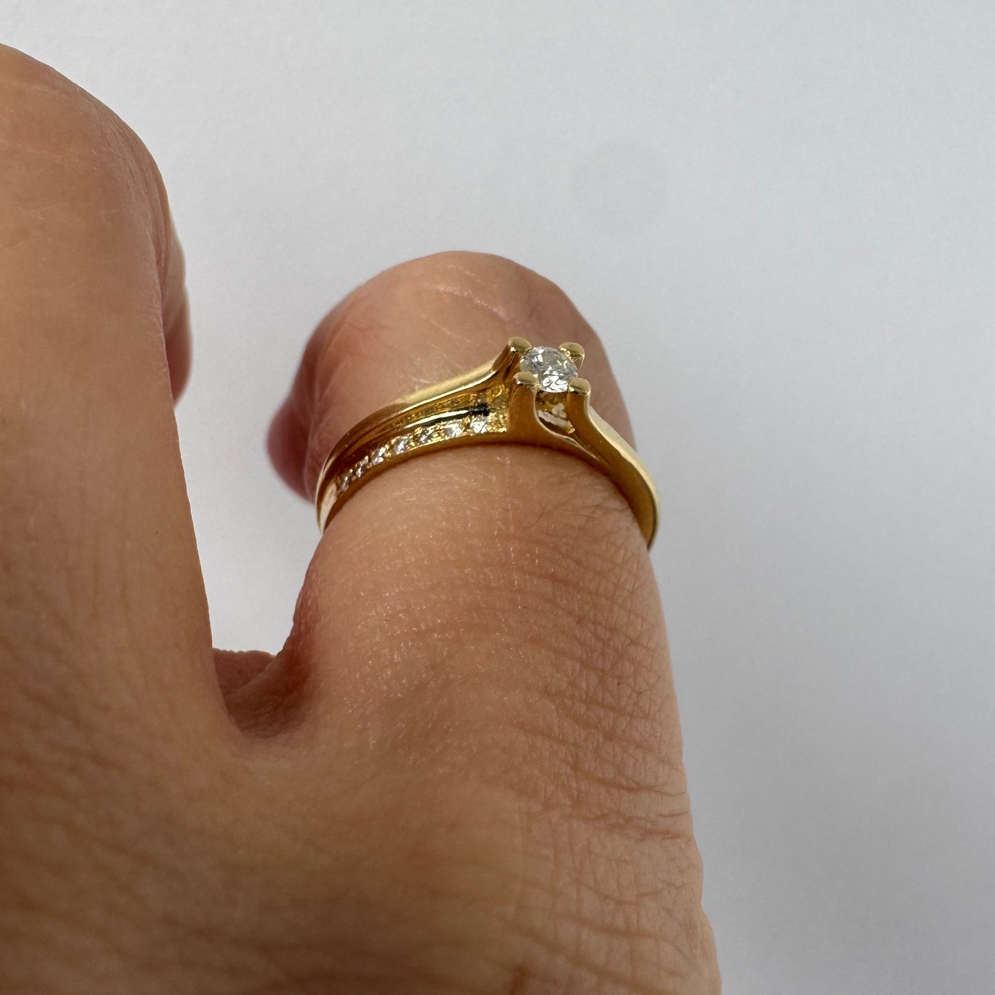 14K yellow gold ring set with a round brilliant-cut diamond and a pavé diamond band ￼