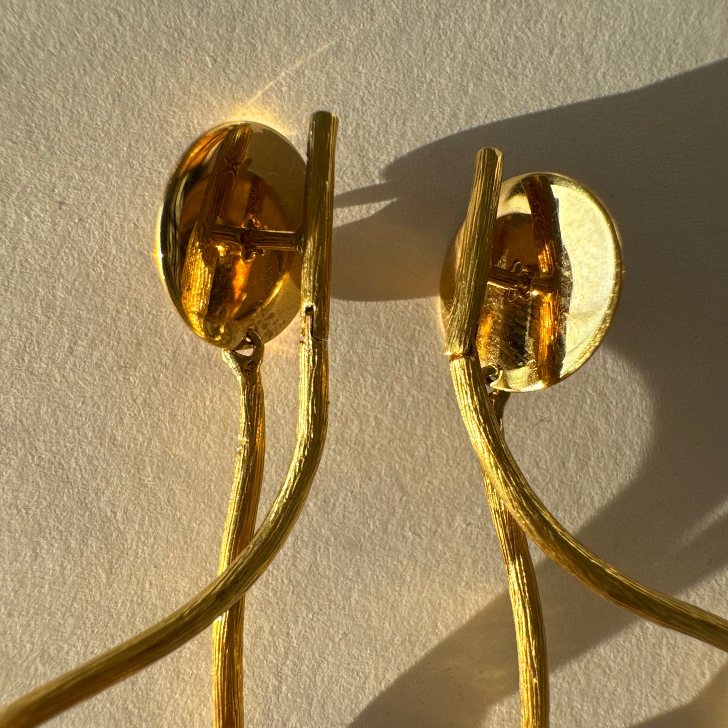 עגילי זהב צהוב 18 קראט מבית ה.שטרן, בעיצוב פיסולי וייחודי עם קווים זורמים ודינמיים.