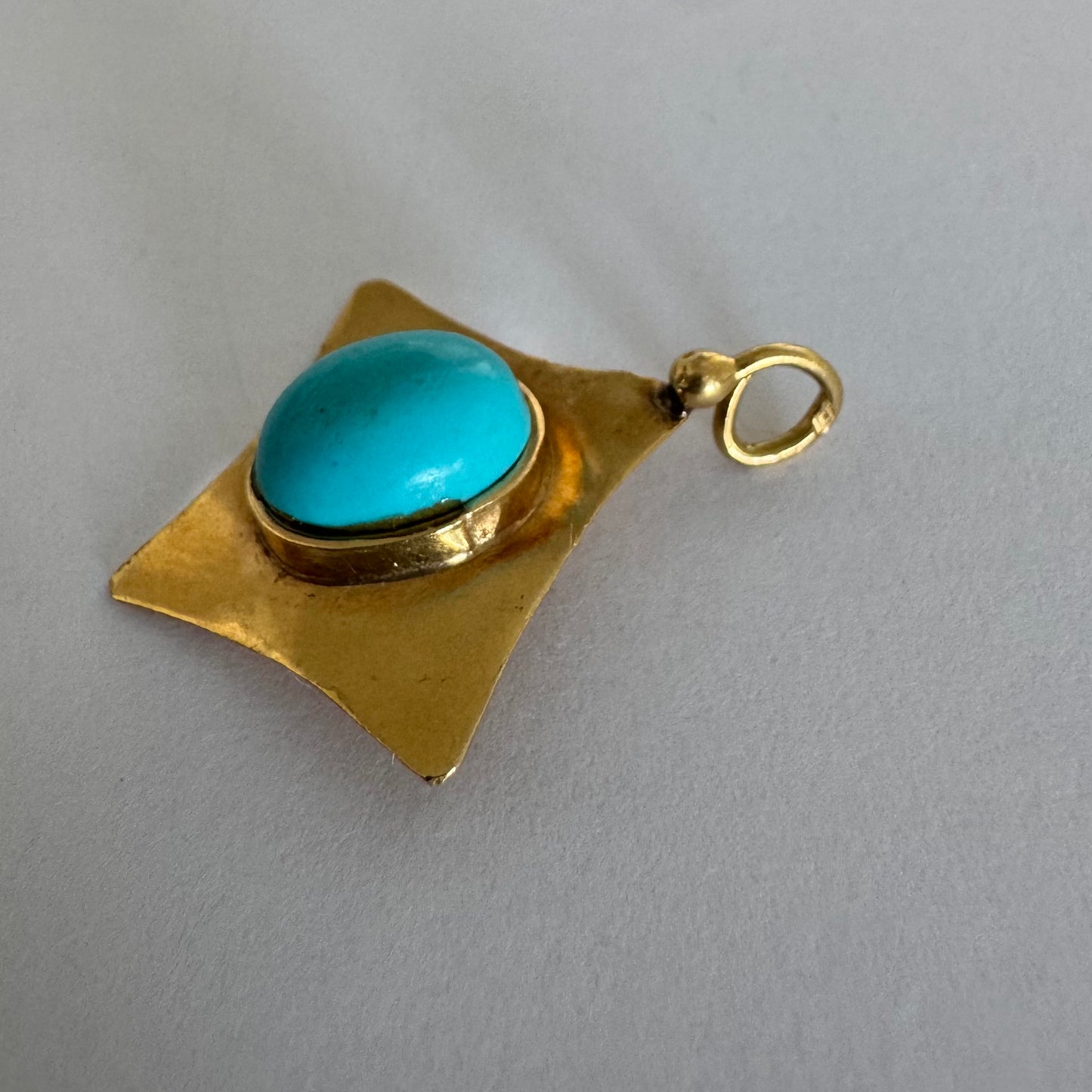 18K gold pendant set with a vibrant Turquoise stone in a bold, geometric design.