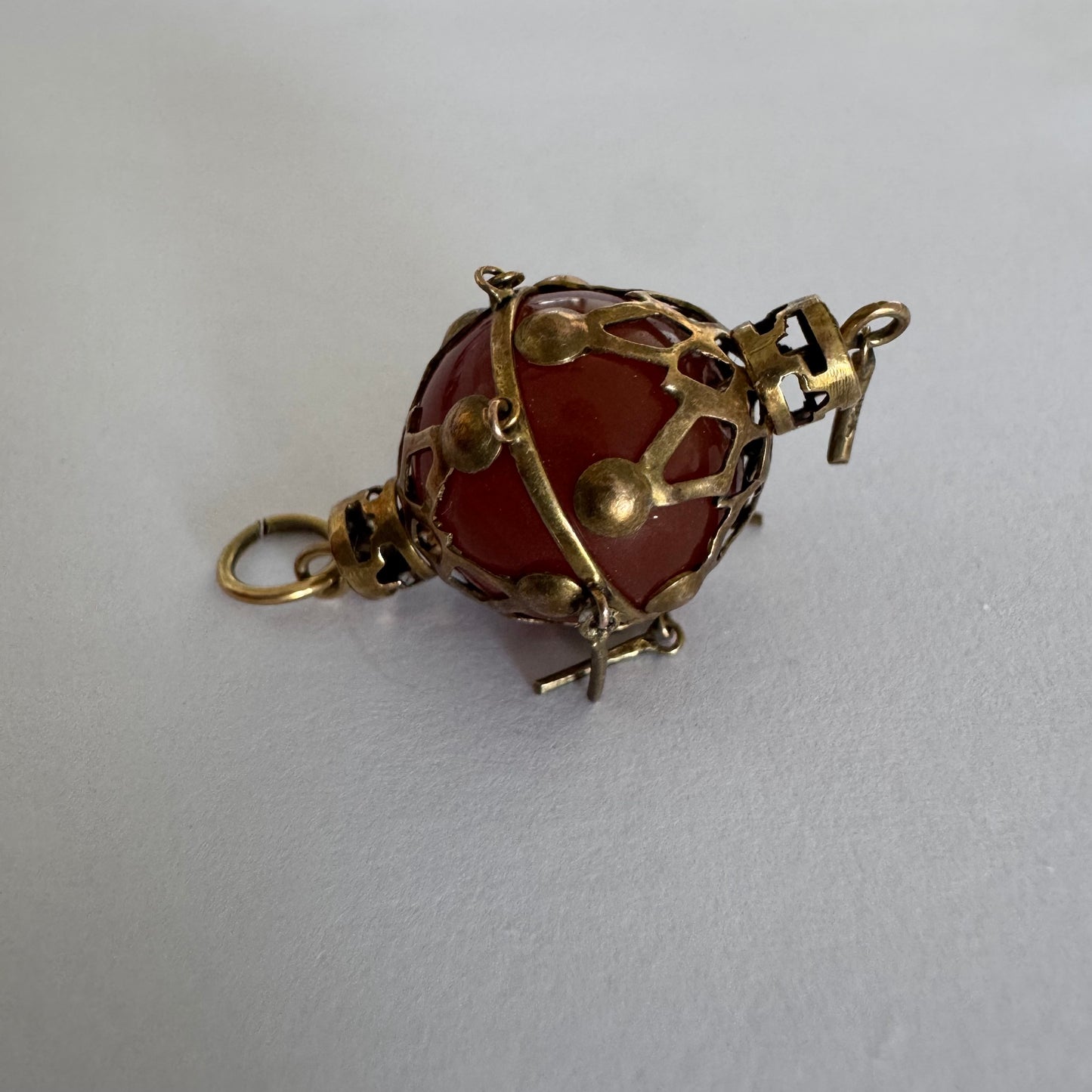 9K gold pendant set with a deep red stone in an intricate openwork design.