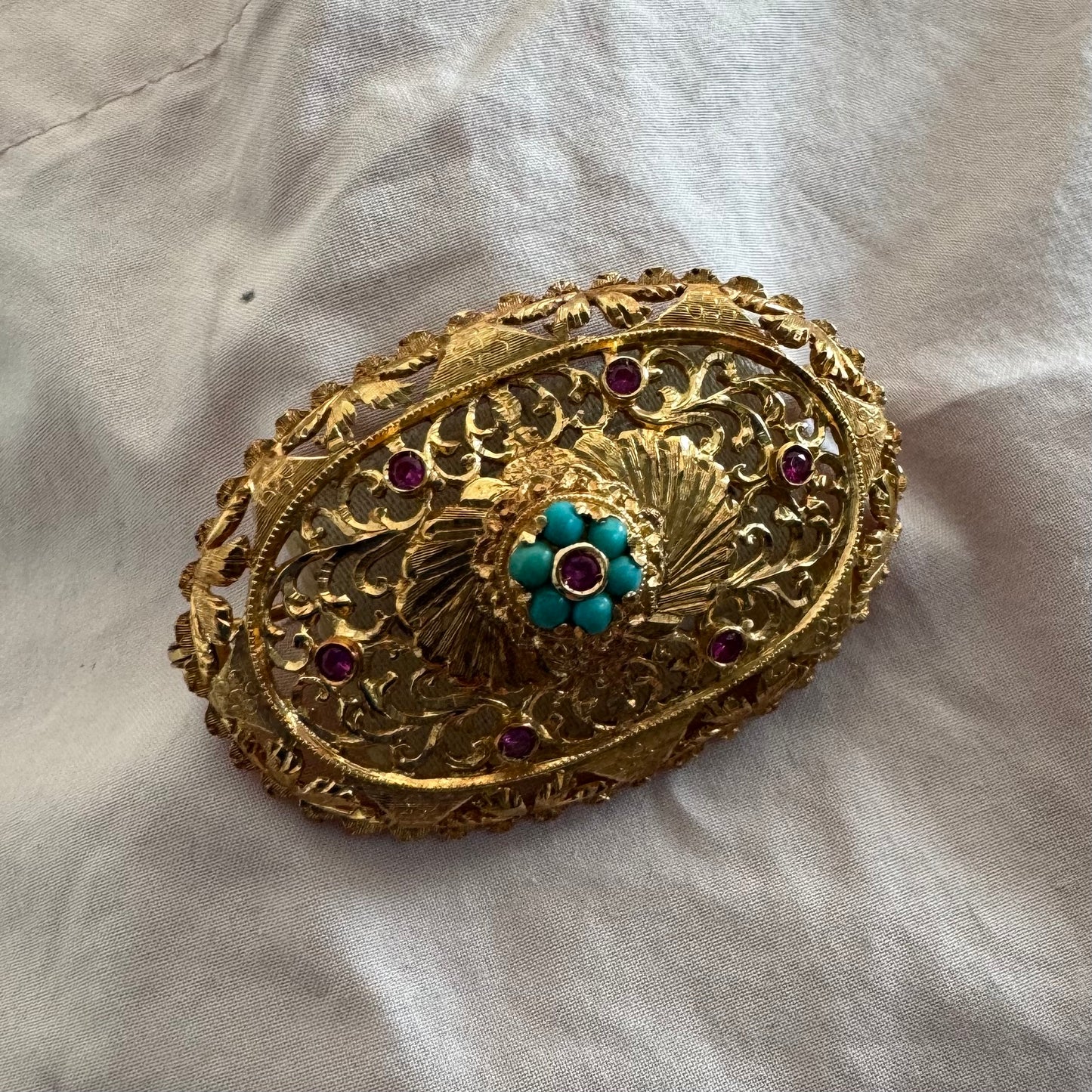 18K gold filigree brooch featuring intricate openwork detailing, accented with Ruby & Turquoise arranged in a floral centerpiece