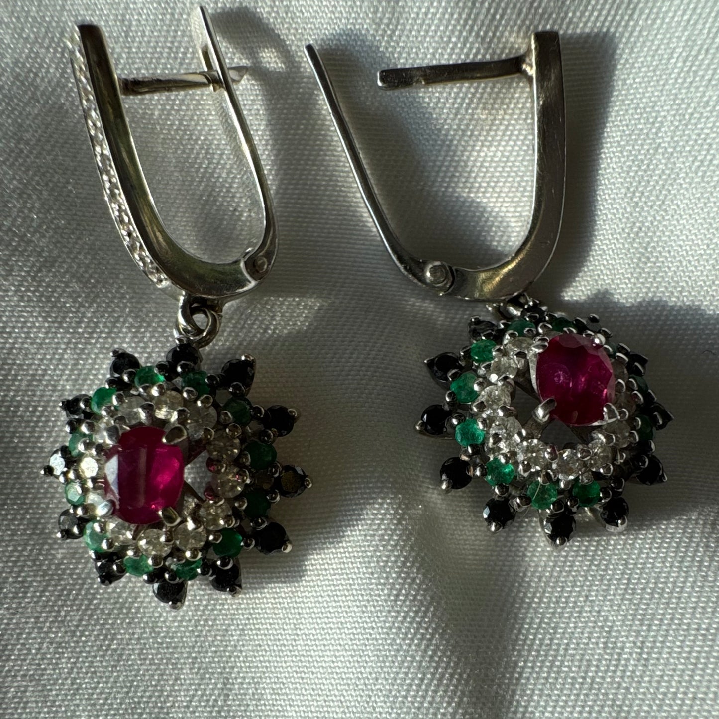 14K white gold drop earrings set with white and black Diamonds, Emeralds and a central Ruby