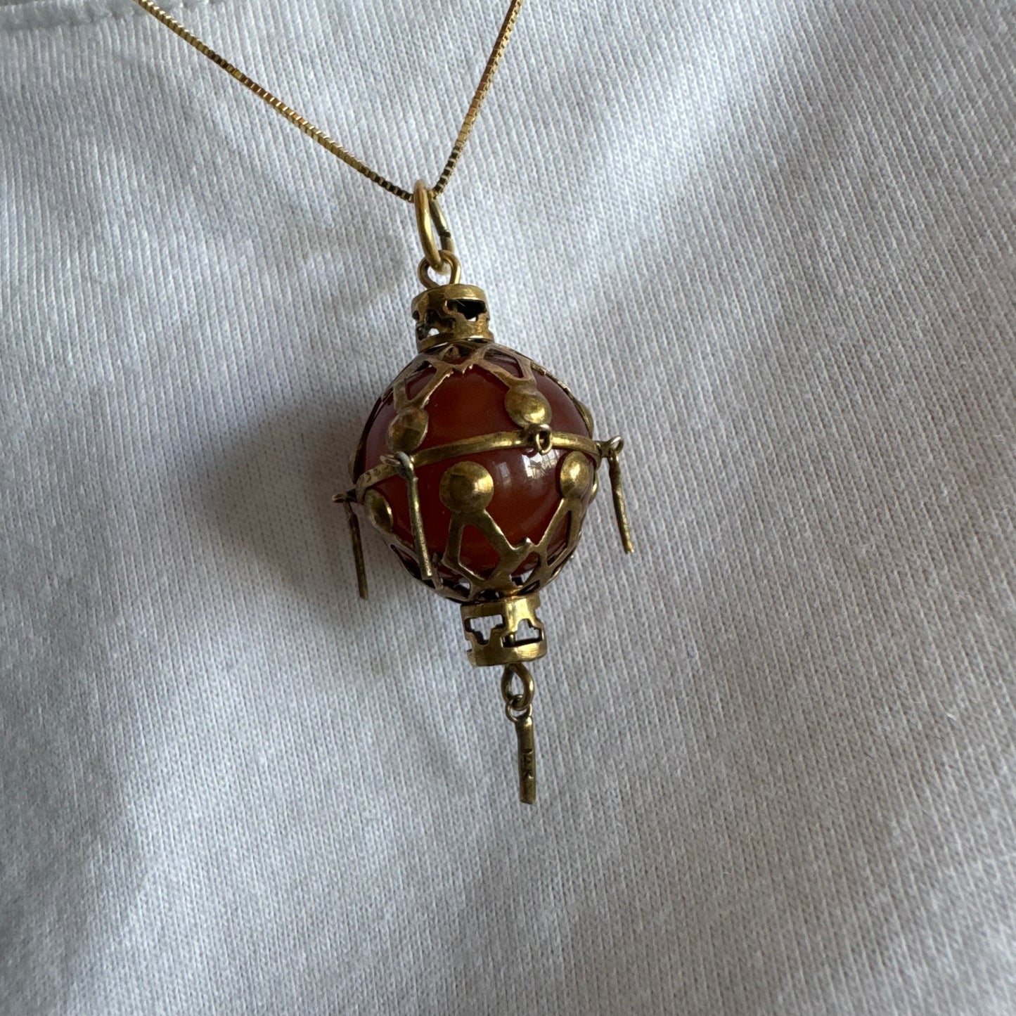 9K gold pendant set with a deep red stone in an intricate openwork design.