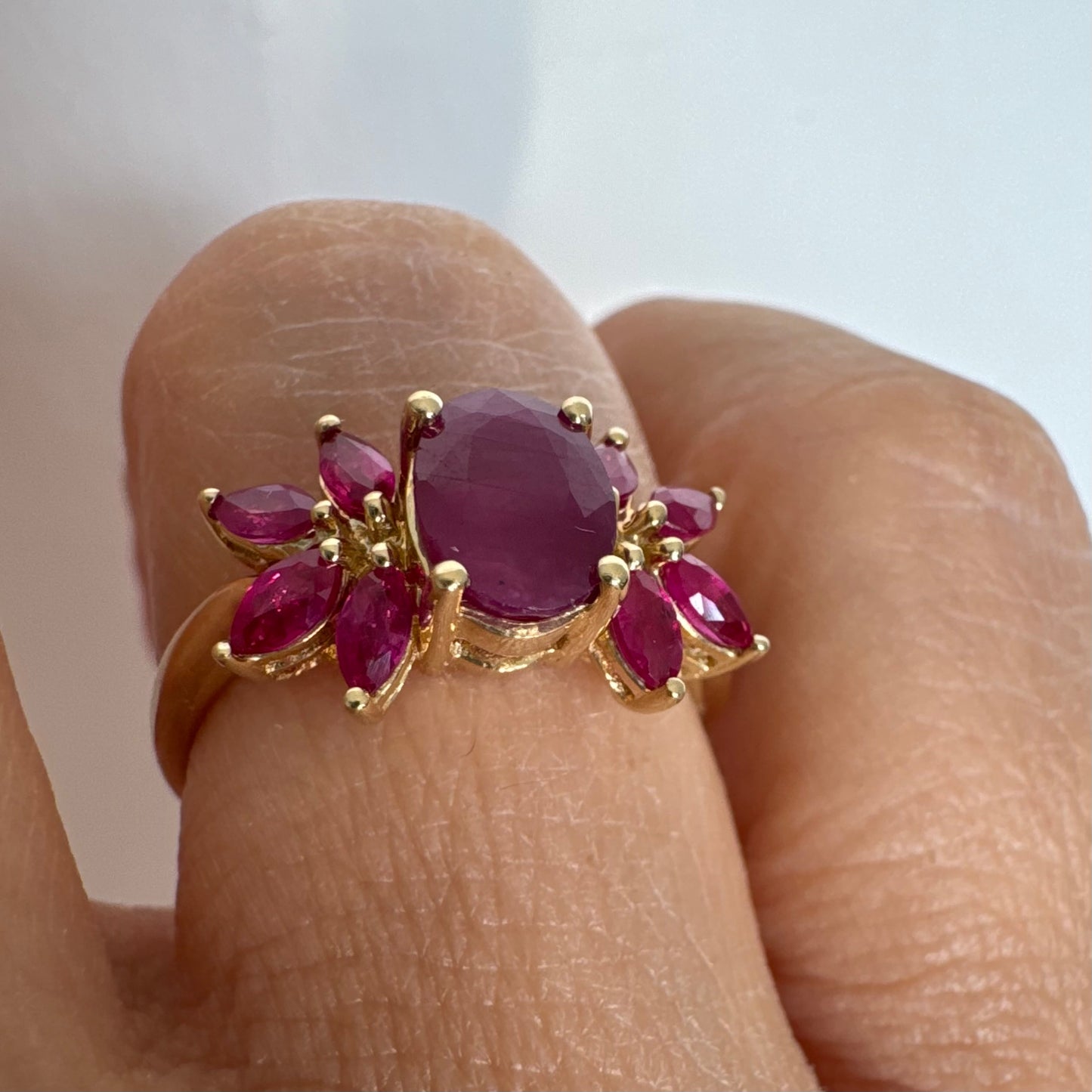 טבעת זהב צהוב 14 קראט משובצת רובי מרכזי גדול ולצידו רובי בחיתוך מרקיזה בעיצוב פרחוני עשיר.