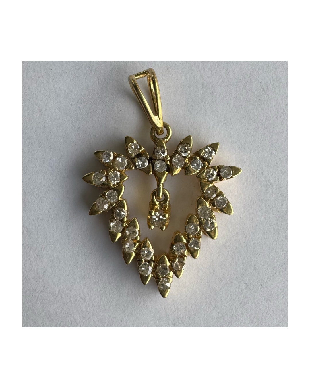 תליון זהב צהוב 14 קראט בצורת לב, משובץ יהלומים בסידור עדין היוצר מראה עשיר ומלא ברק.