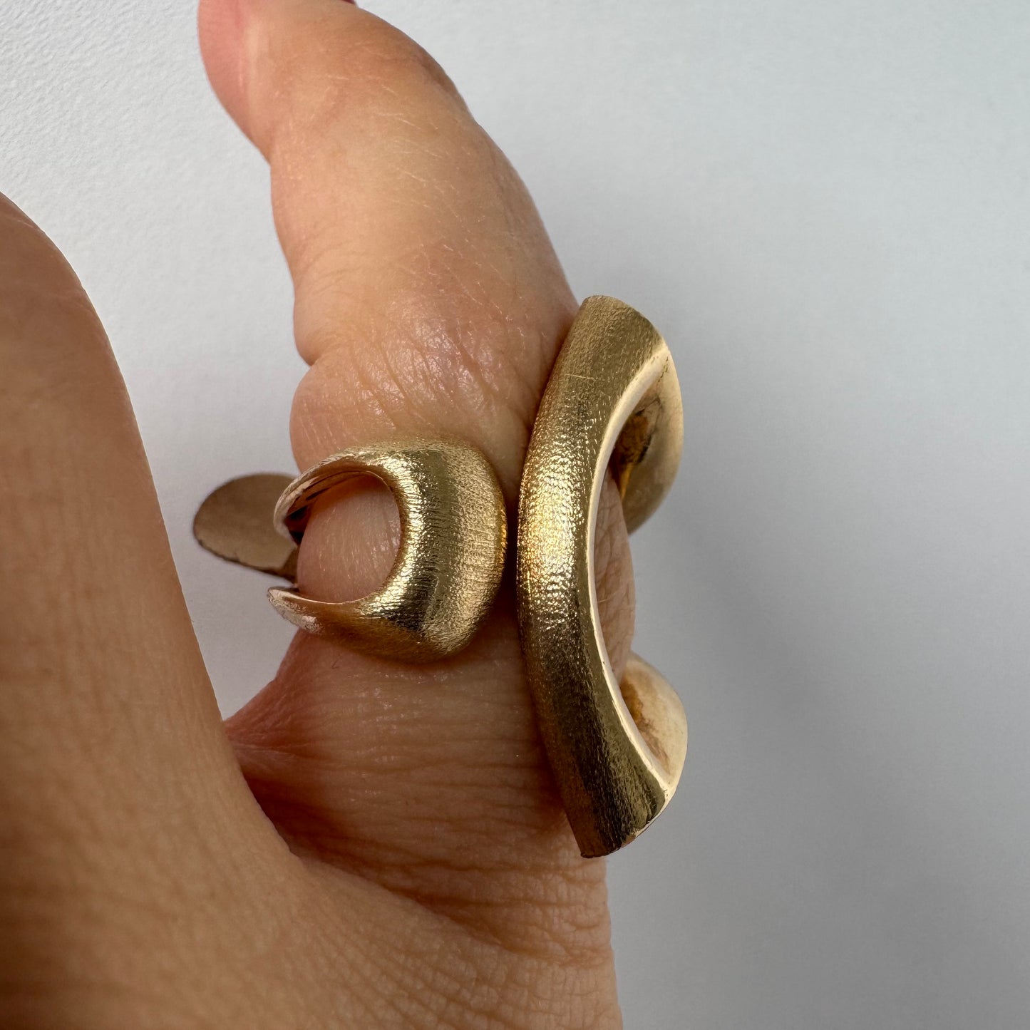 14K gold sculptural ring with a bold, modern design featuring flowing, asymmetrical lines.