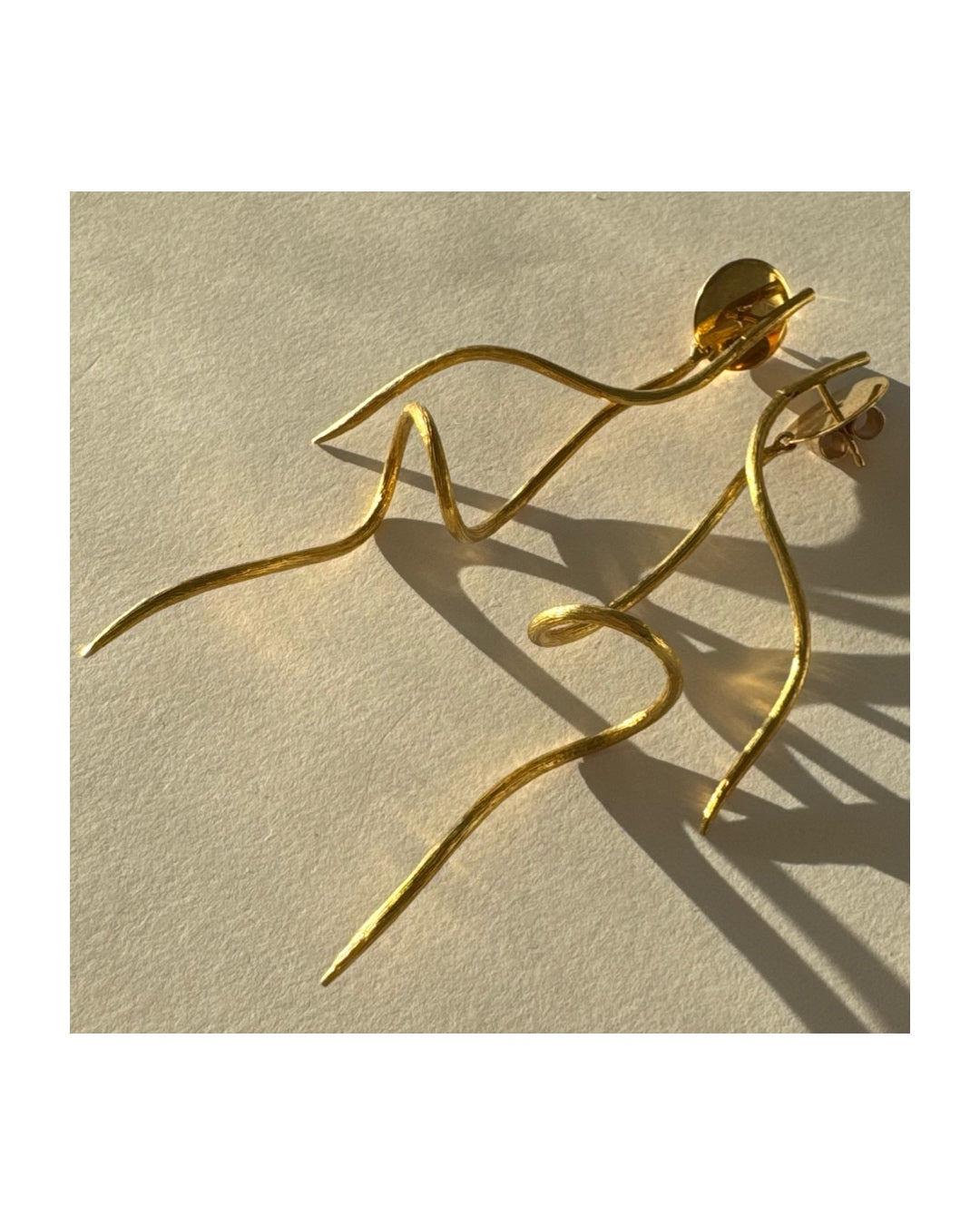 עגילי זהב צהוב 18 קראט מבית ה.שטרן, בעיצוב פיסולי וייחודי עם קווים זורמים ודינמיים.