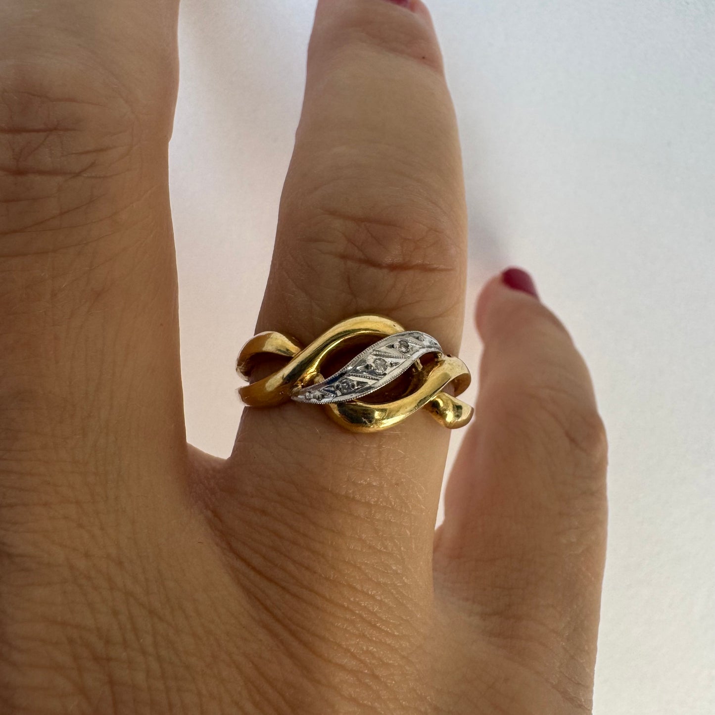 18K gold knot-style ring featuring a white gold center accented with delicate Diamonds.