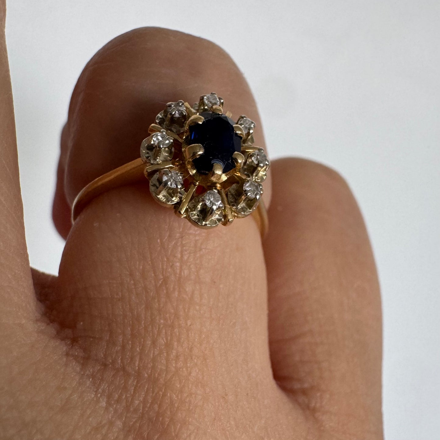 18K gold ring set with a natural blue Sapphire at its center, surrounded by a halo of sparkling Diamonds